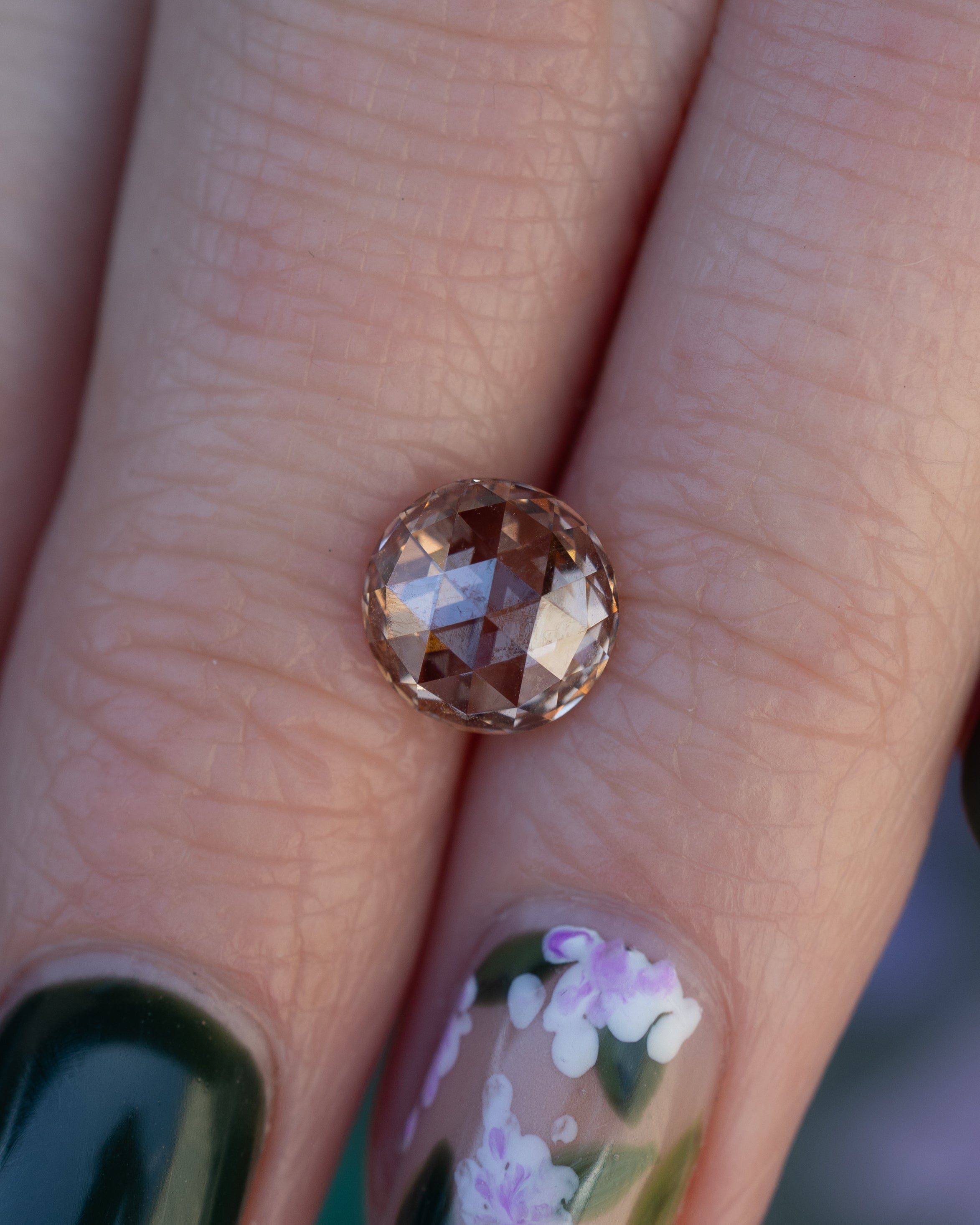 Close-up of fingers holding a round champagne diamond