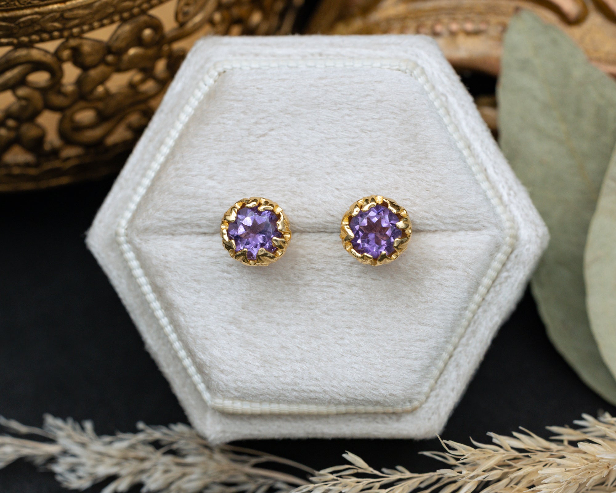 Pair of purple amethyst earrings in a hexagonal white jewelry box.