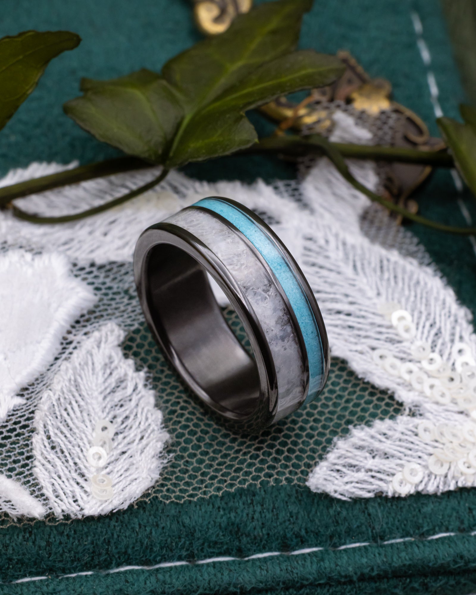 Black zirconium ring with turquoise and wedding dress inlay on a lace and decorative background