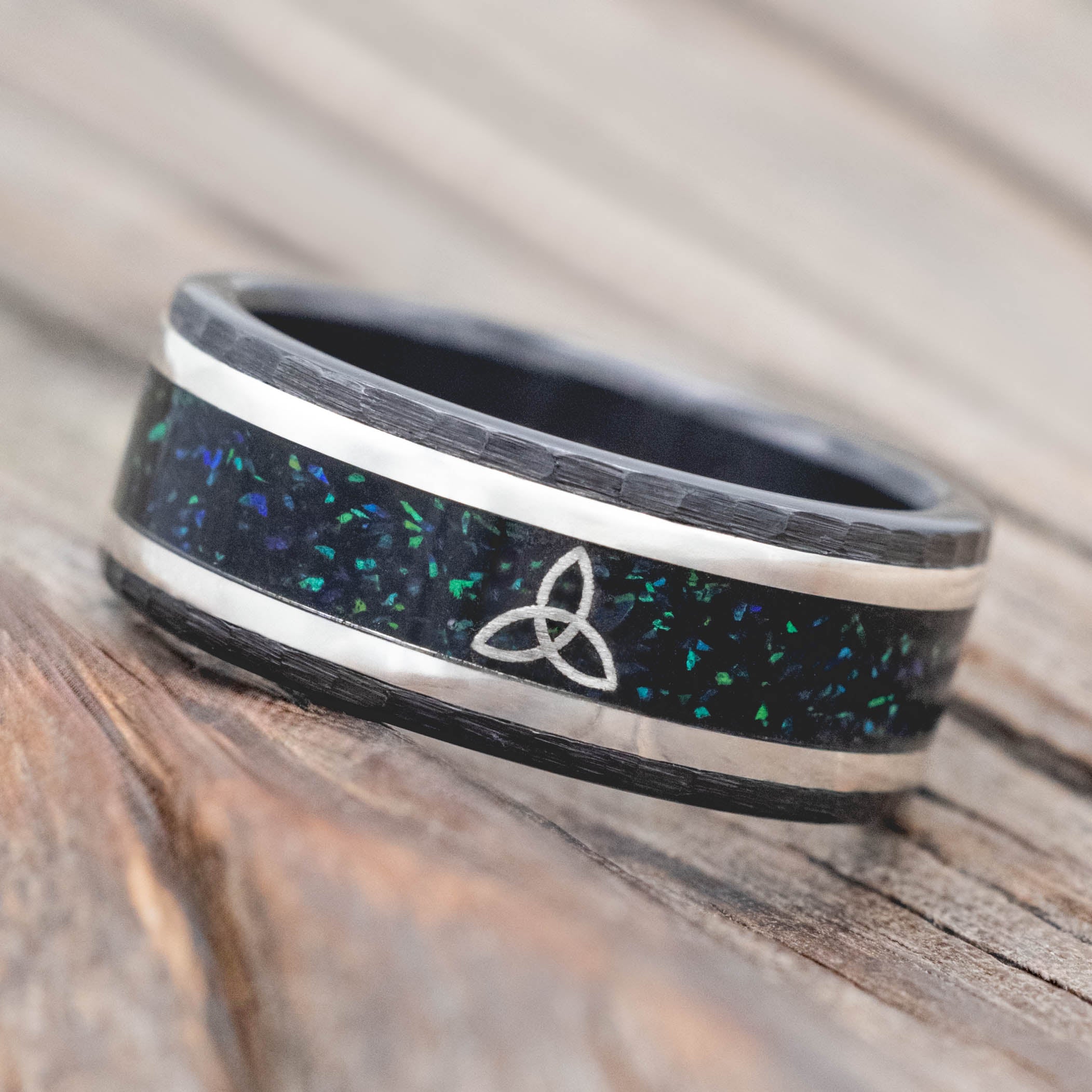 Black ring with a Celtic knot design on a wooden surface