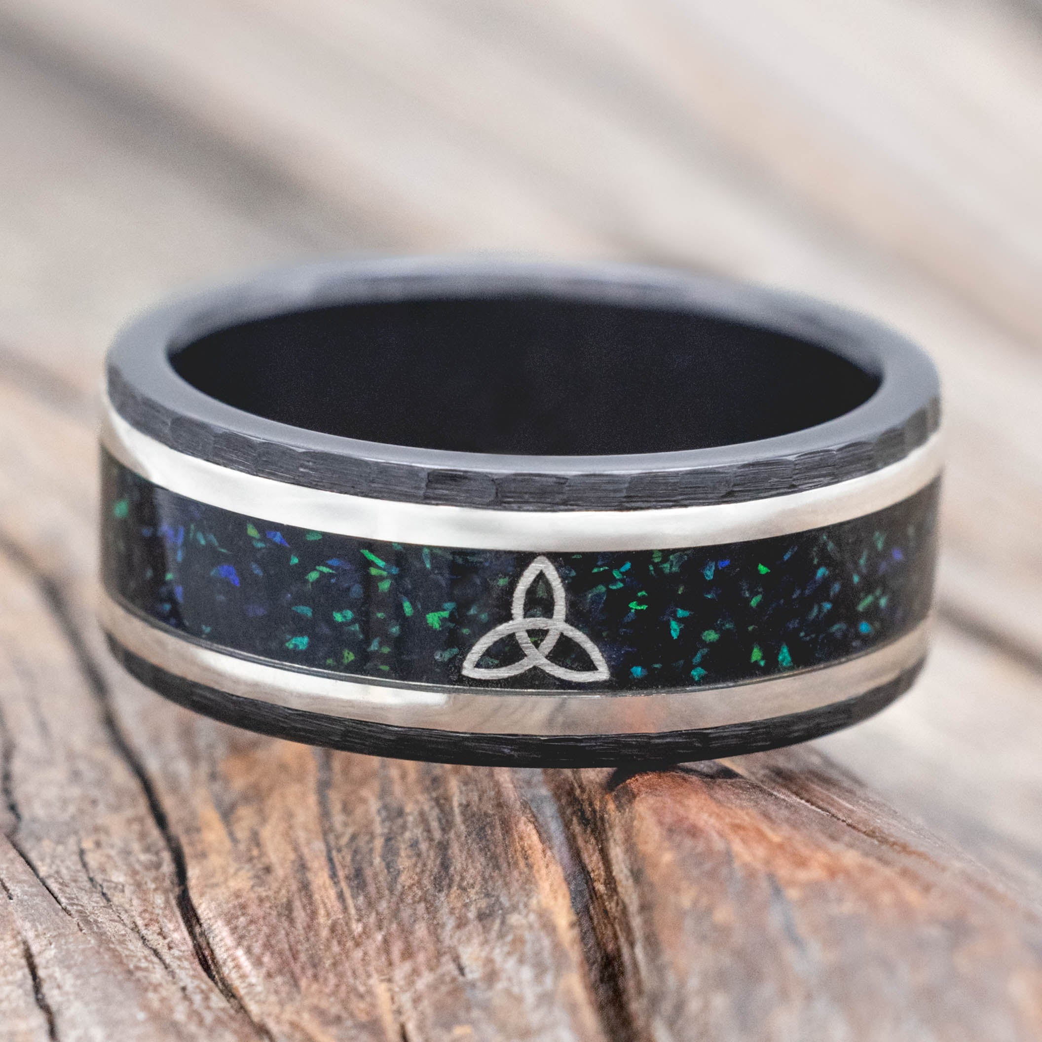 Black ring with a Celtic knot design on a wooden surface