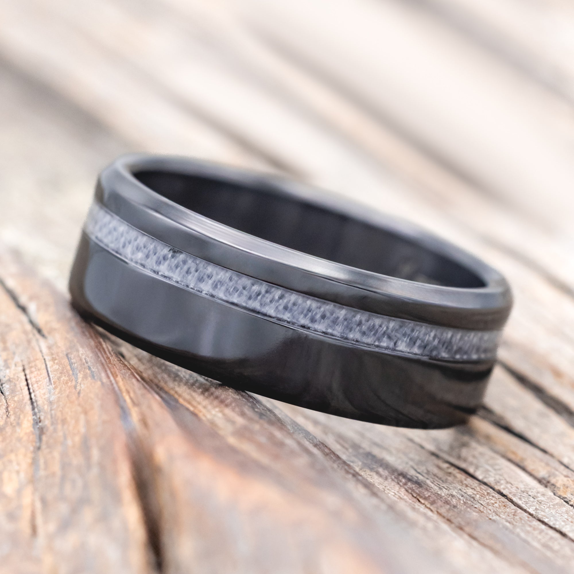 black zirconium wedding ring with wedding dress inlay on wooden surface