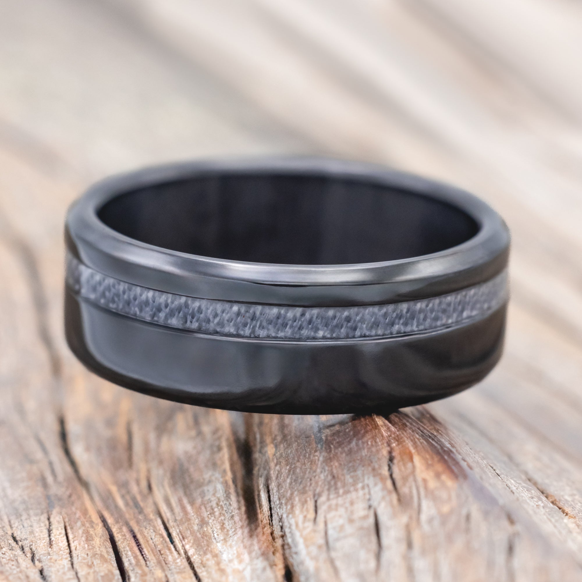 black zirconium wedding ring with wedding dress inlay on wooden surface