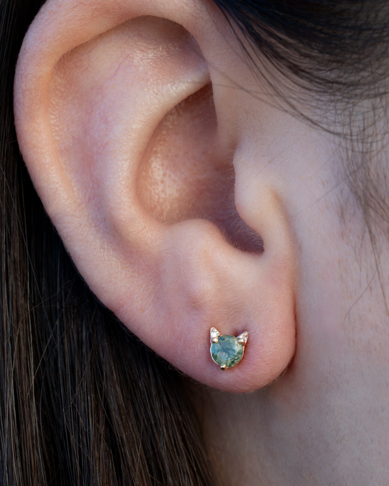 Moss agate cat earring on the ear against dark hair