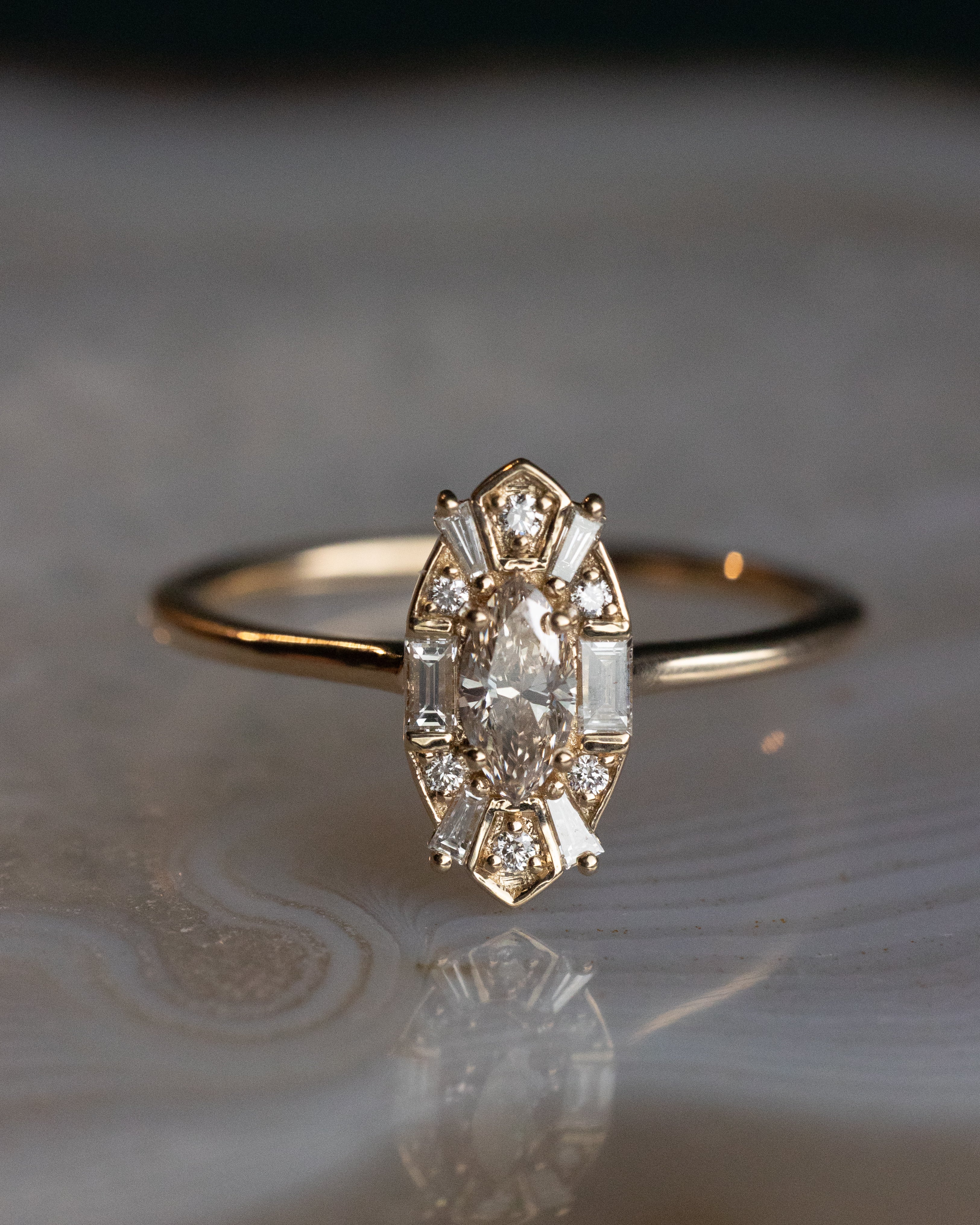 Gold ring with champagne diamond center stone and diamond accents on an agate surface