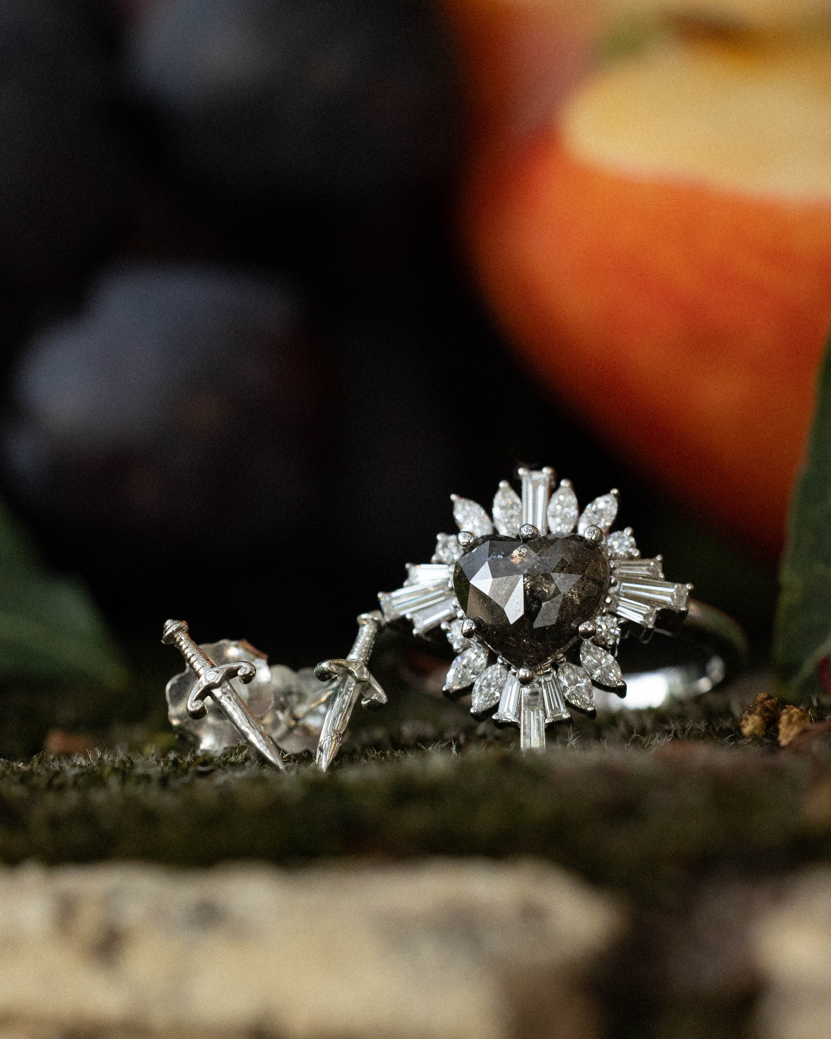Lifestyle photo of "Autumn" - closeup of women's engagement ring with heart cut salt & pepper diamond and silver dagger earrings