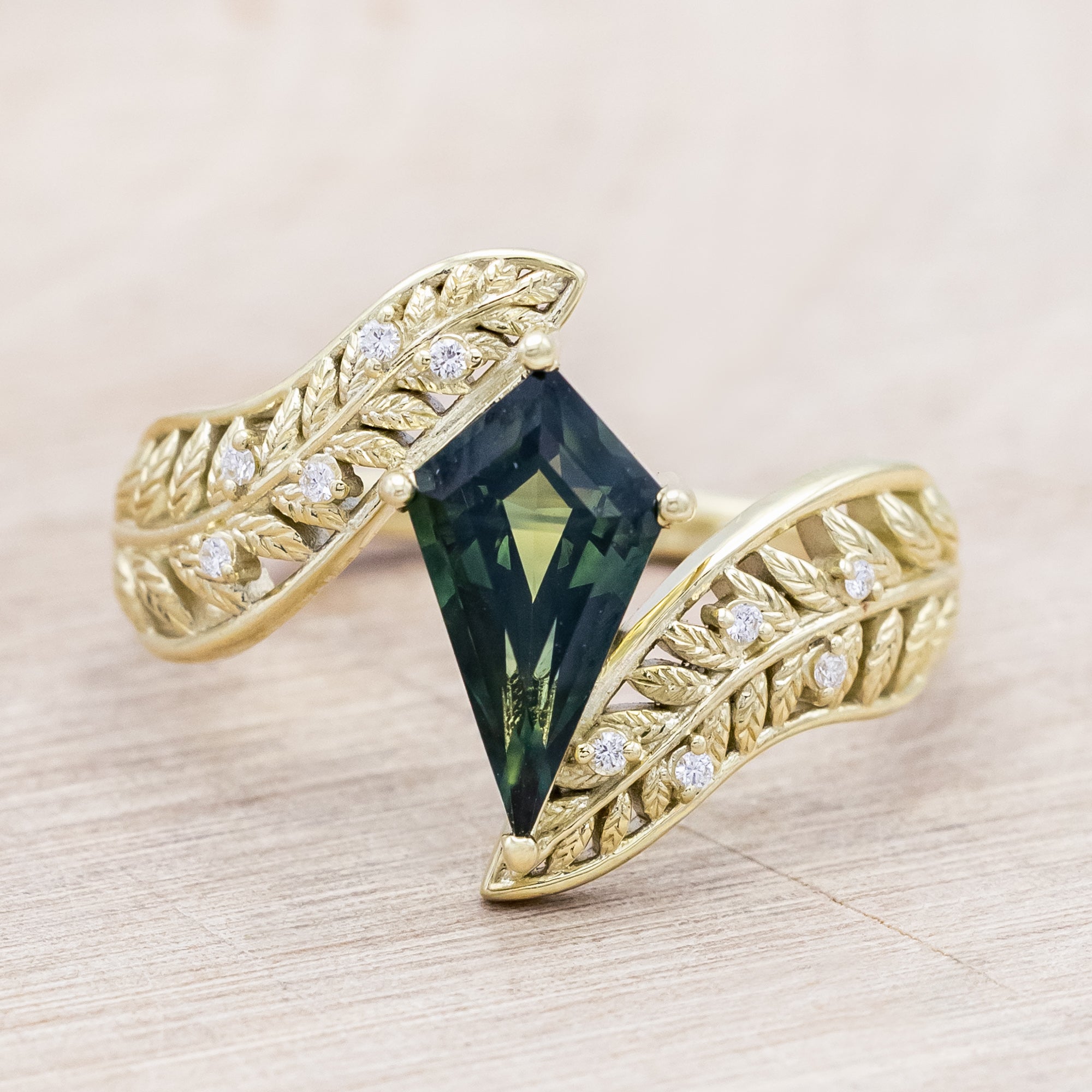 Green gold ring with a green sapphire on a light wooden surface