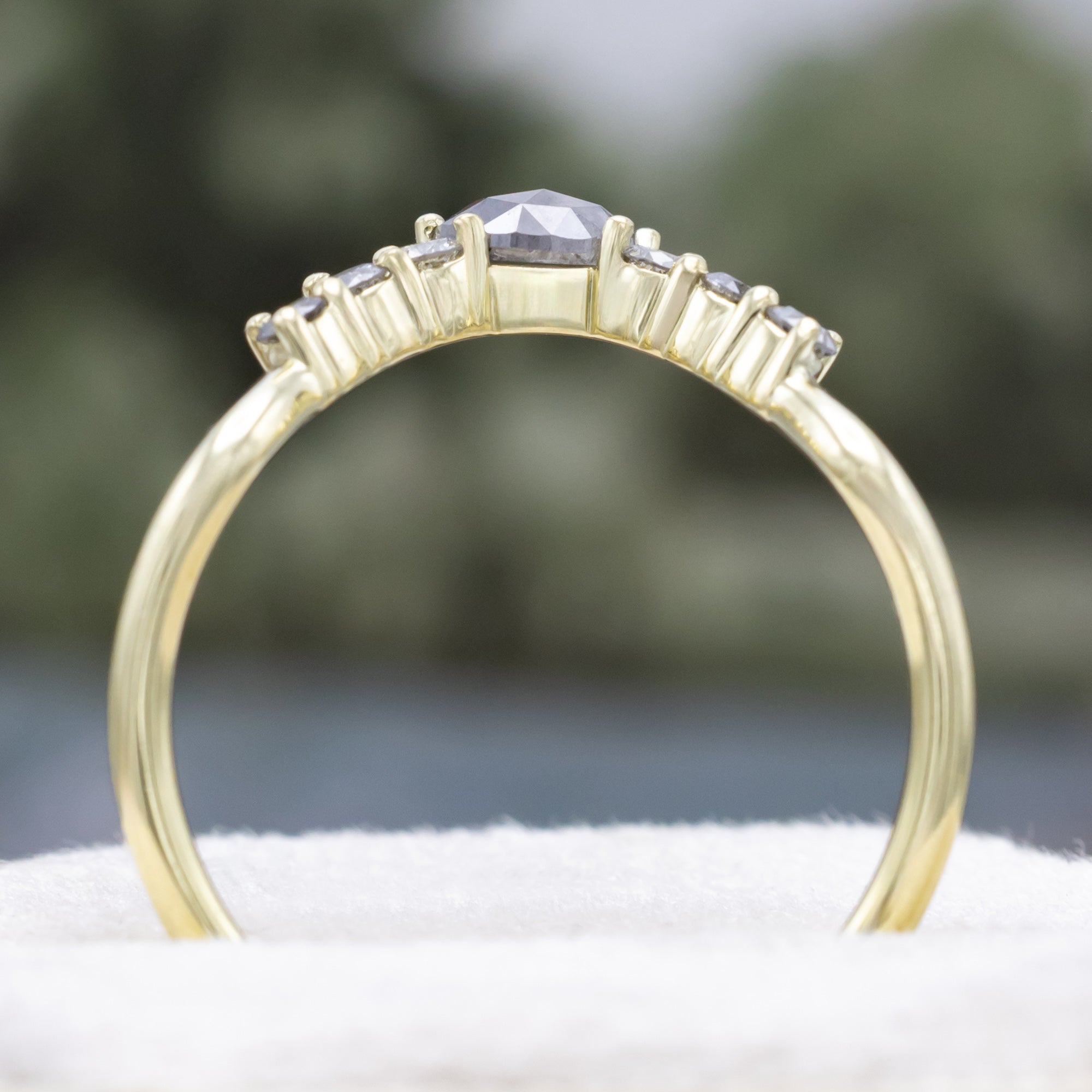 Green gold ring with salt & pepper diamond accents on a neutral background