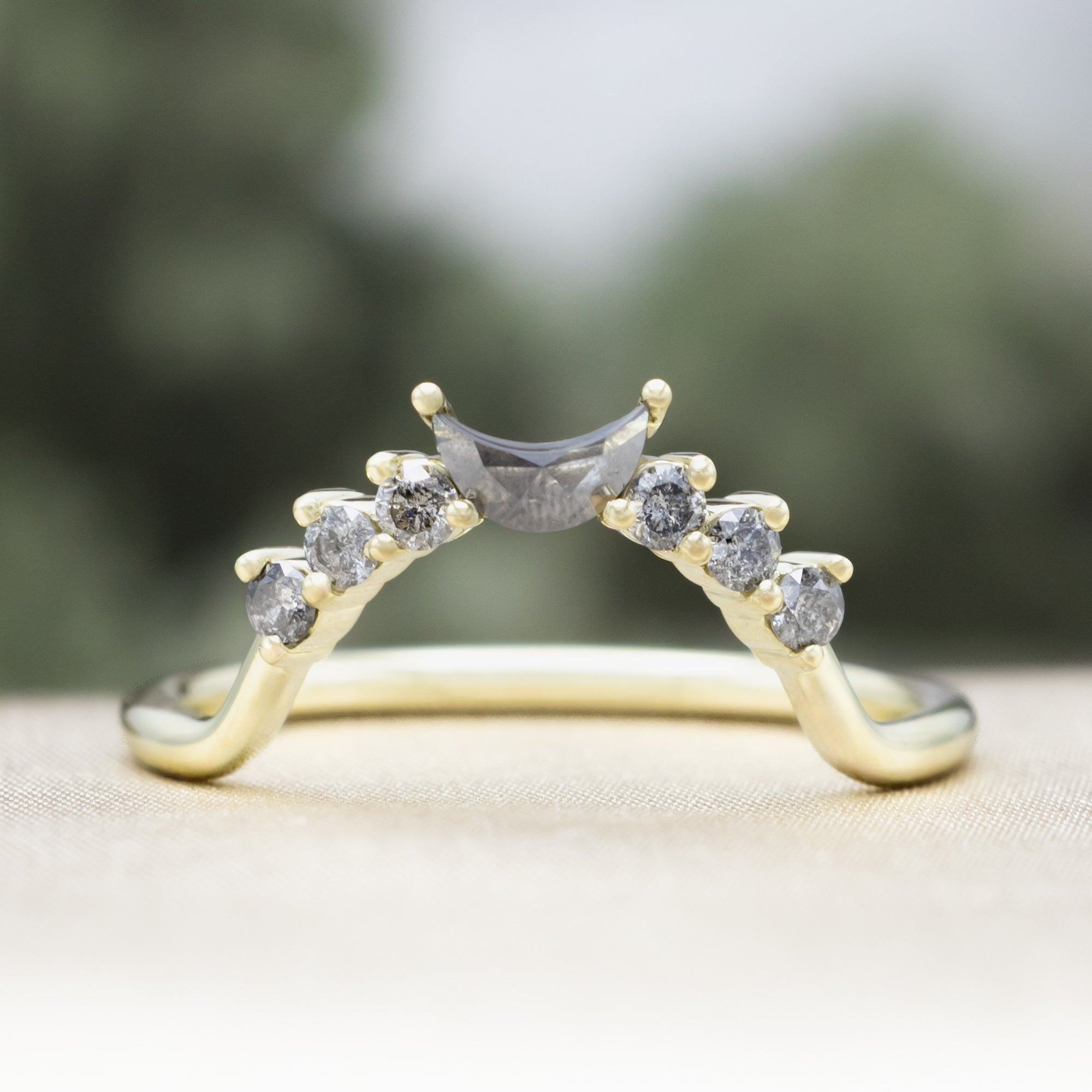 Green gold ring with salt & pepper diamond accents on a neutral background