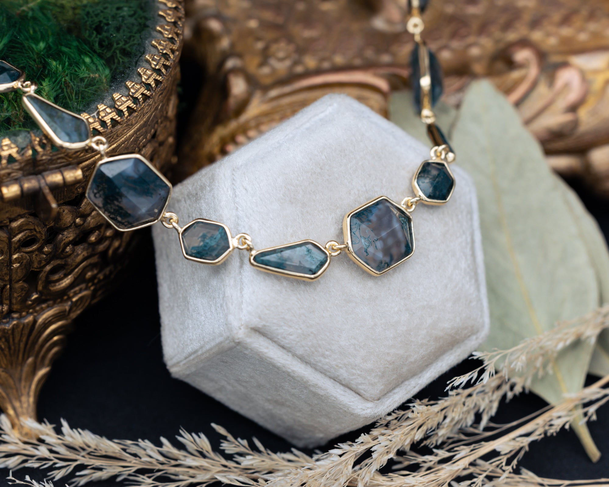 Necklace with moss agate pendants on a white stand with a decorative background