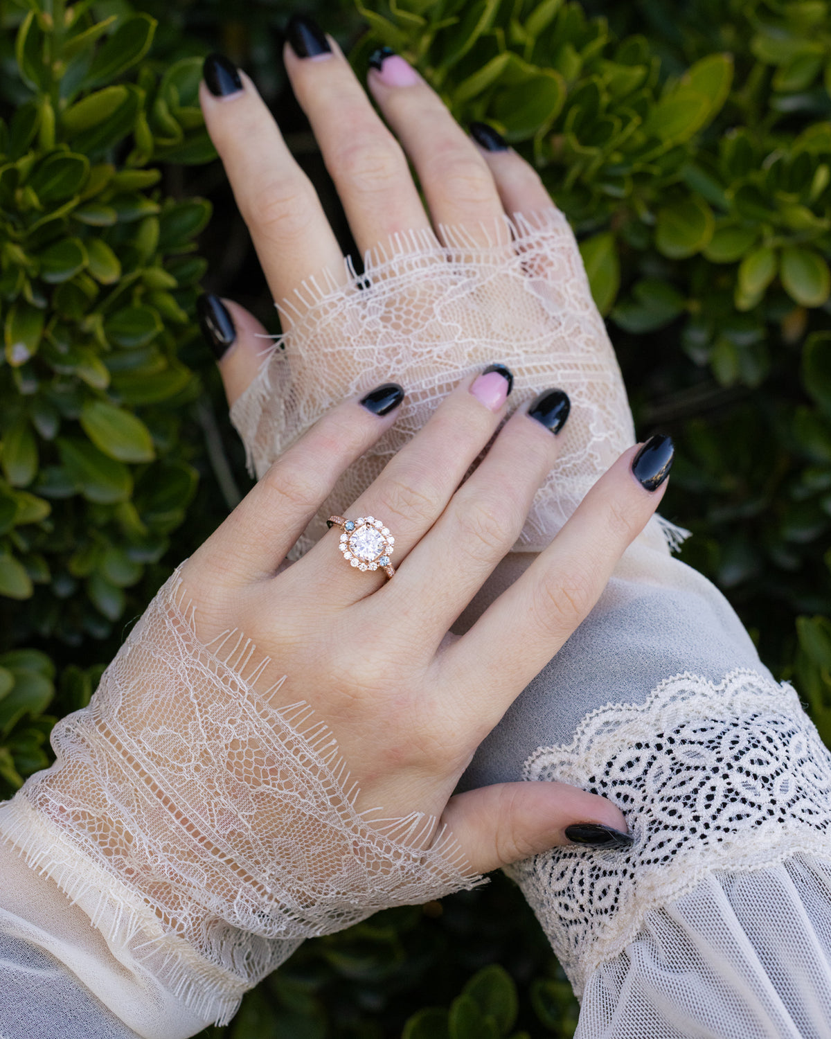 Hand wearing a lace sleeve and a ring with a green leafy background