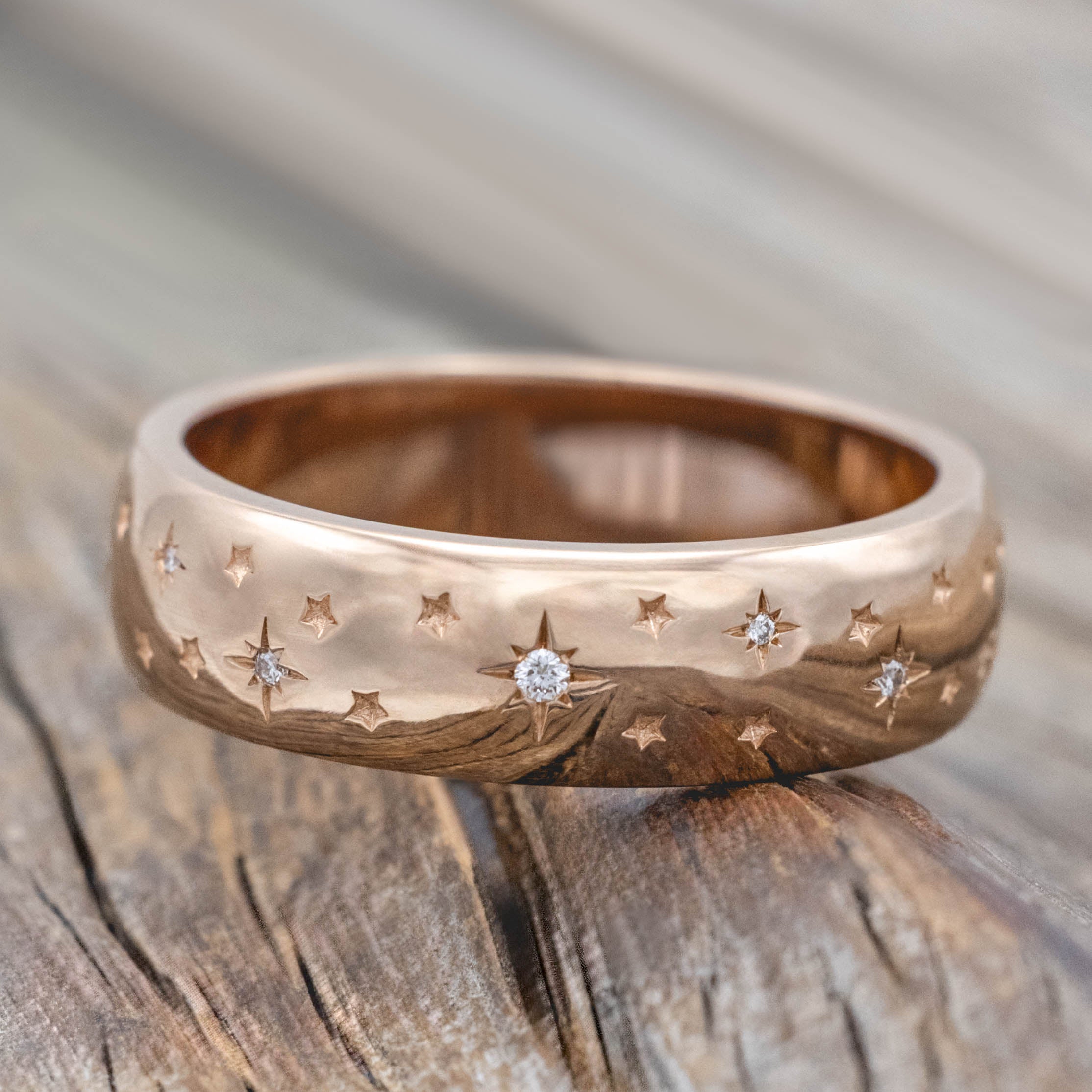 14K rose gold ring with star designs inset with diamonds on a wooden surface