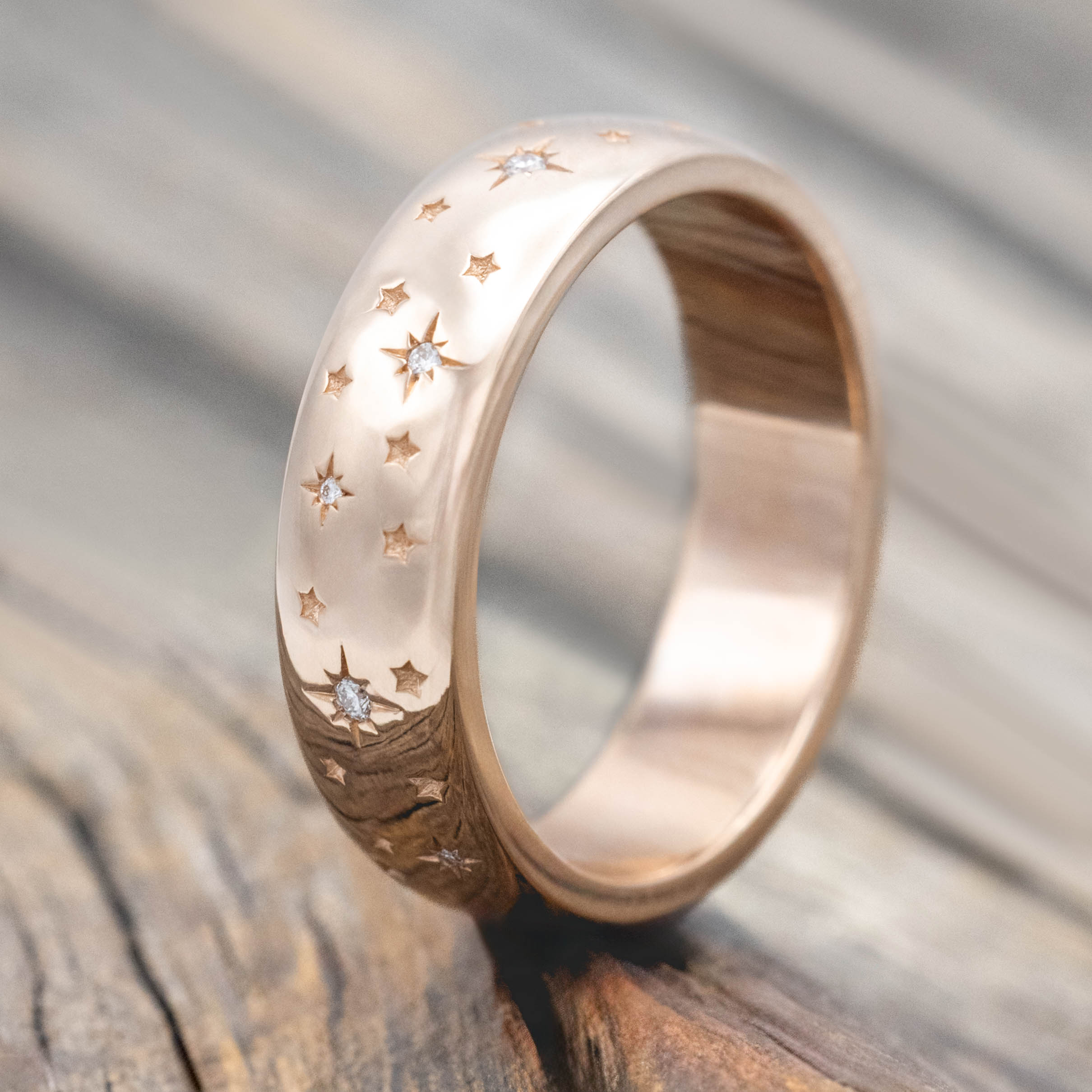 14K rose gold ring with star designs inset with diamonds on a wooden surface