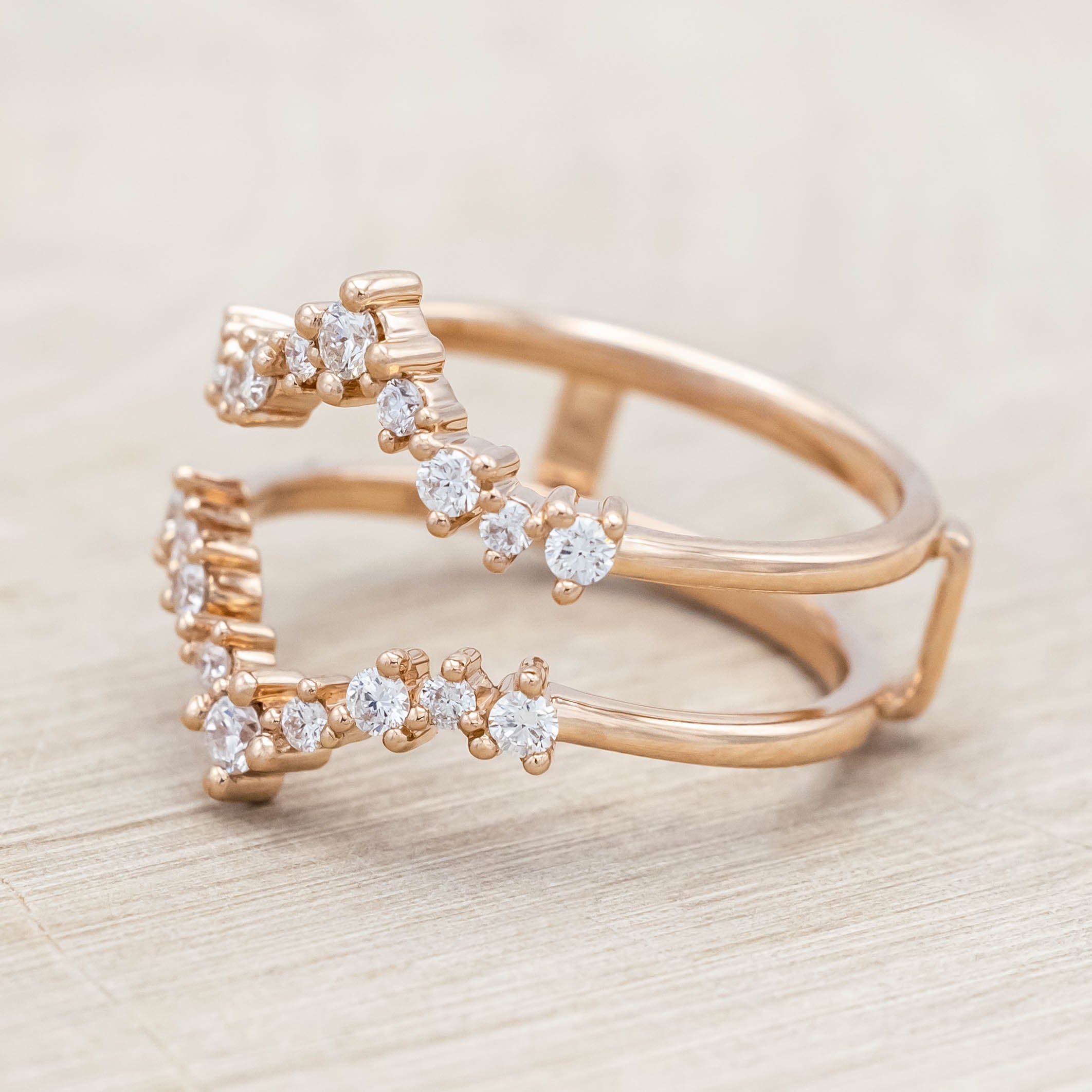 14K rose gold ring with diamond accents on a light wooden surface