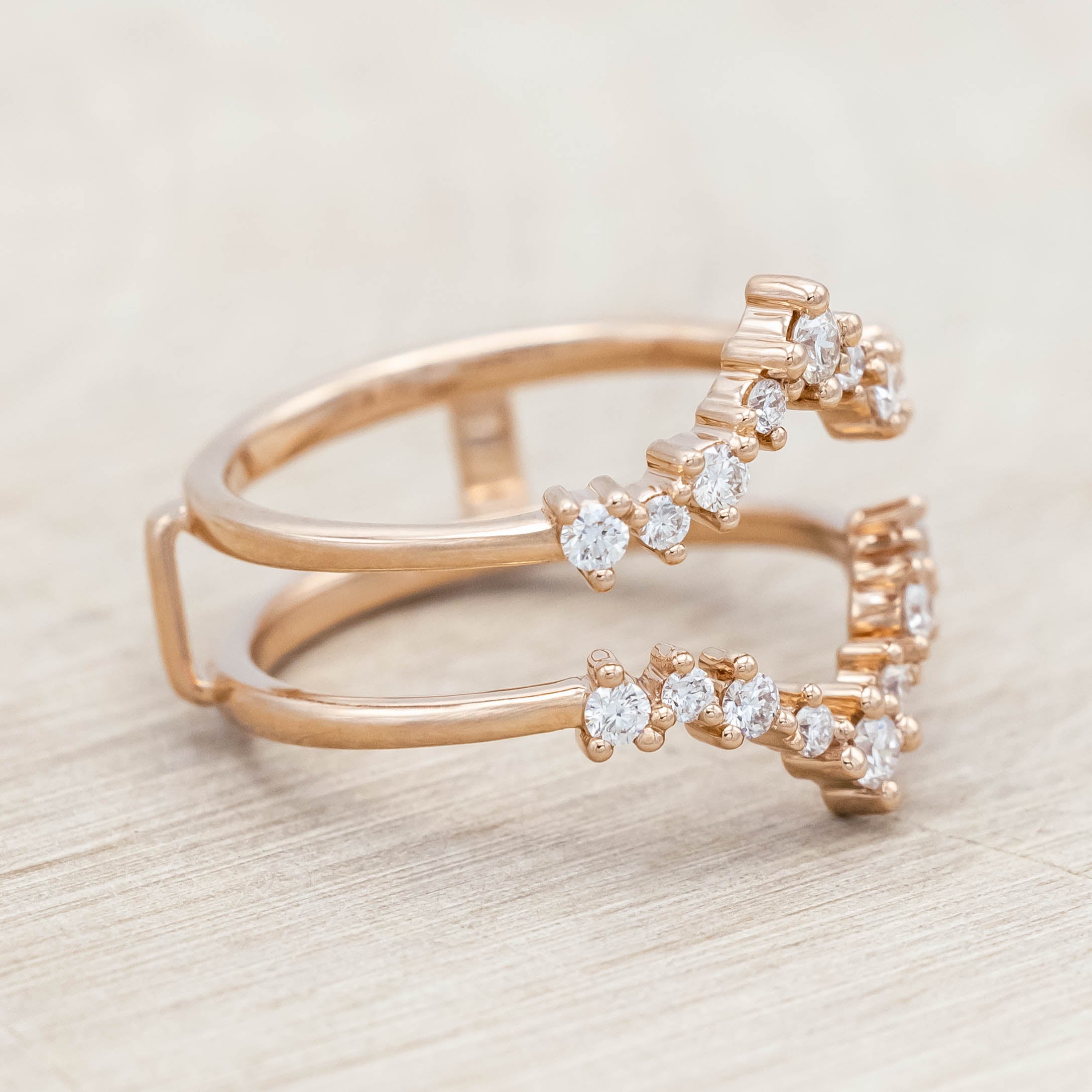 14K rose gold ring with diamond accents on a light wooden surface