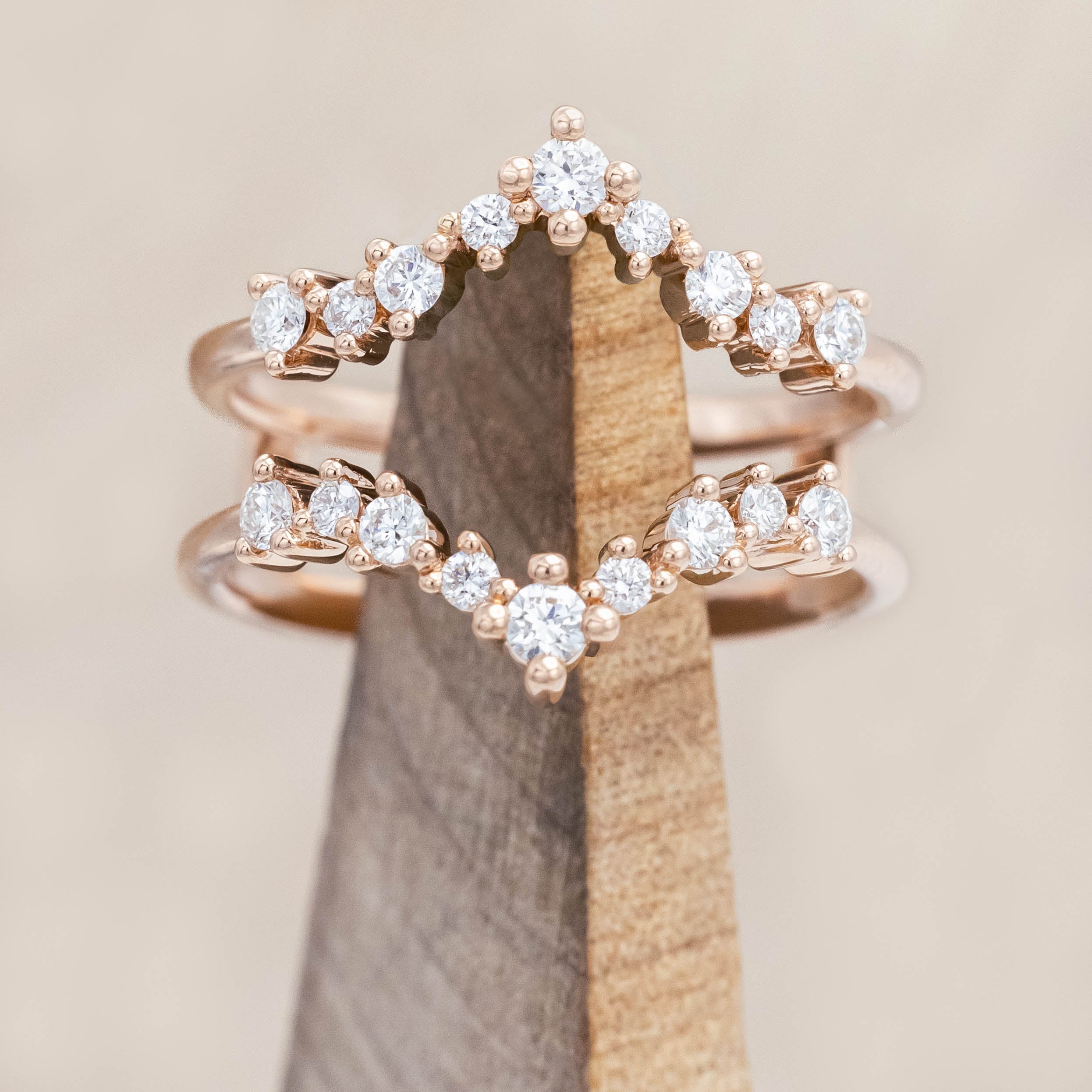 14K rose gold ring with diamond accents on a wooden block against a beige background