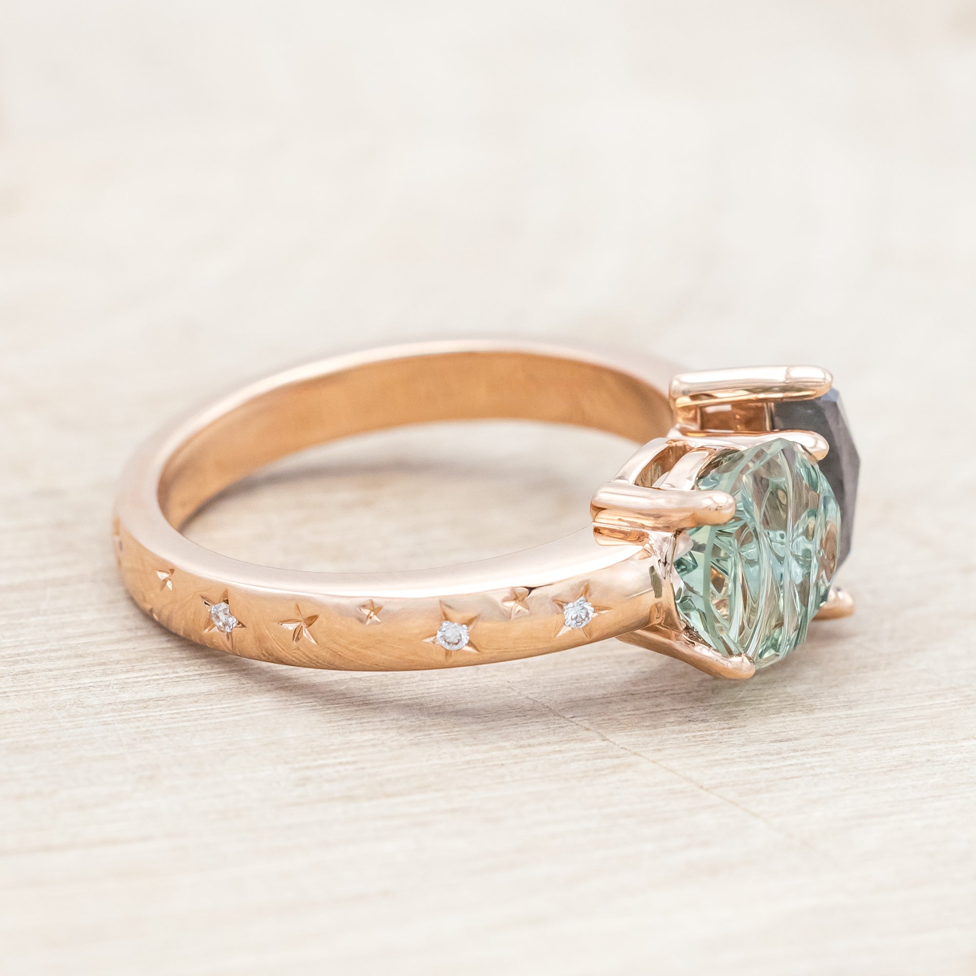 Ring with green sapphire and salt & pepper diamond and rose gold band on a neutral background
