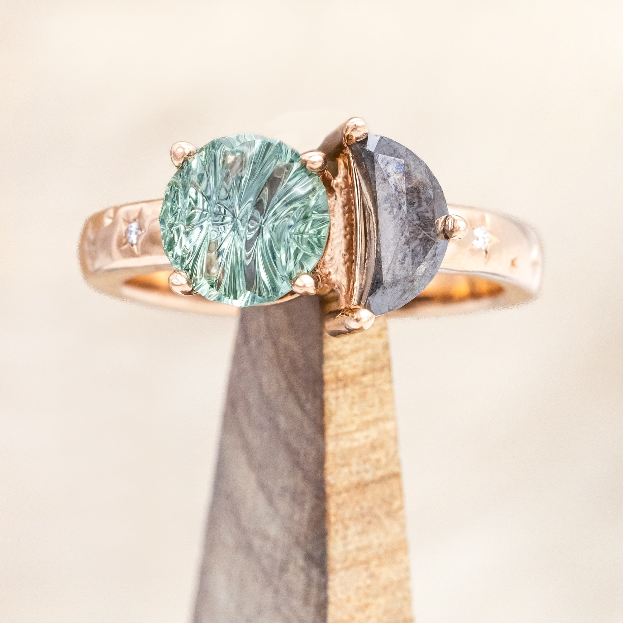 Ring with green sapphire and salt & pepper diamond and rose gold band on a neutral background