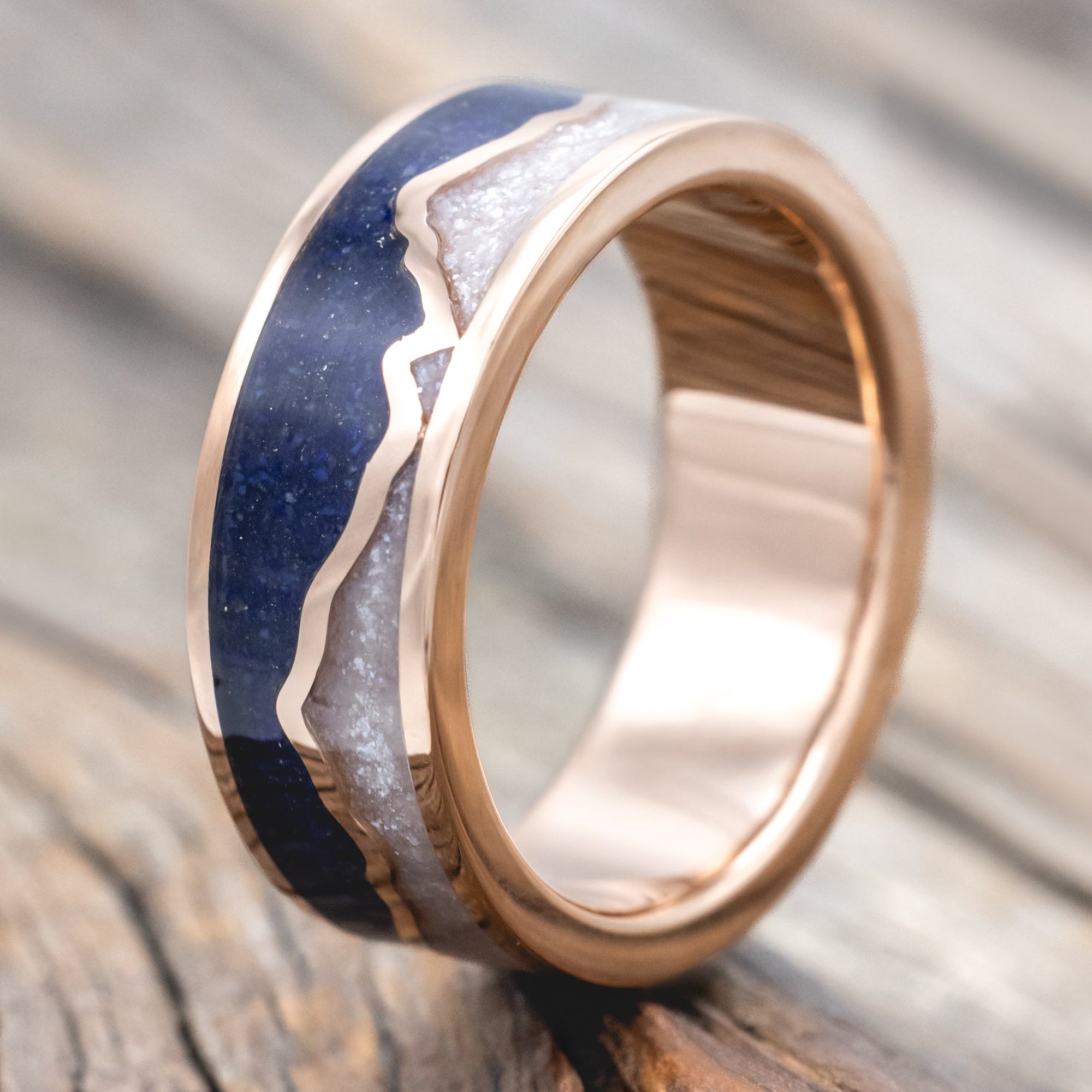 Rose gold ring with lapis lazuli and diamond dust inlay on a wooden surface