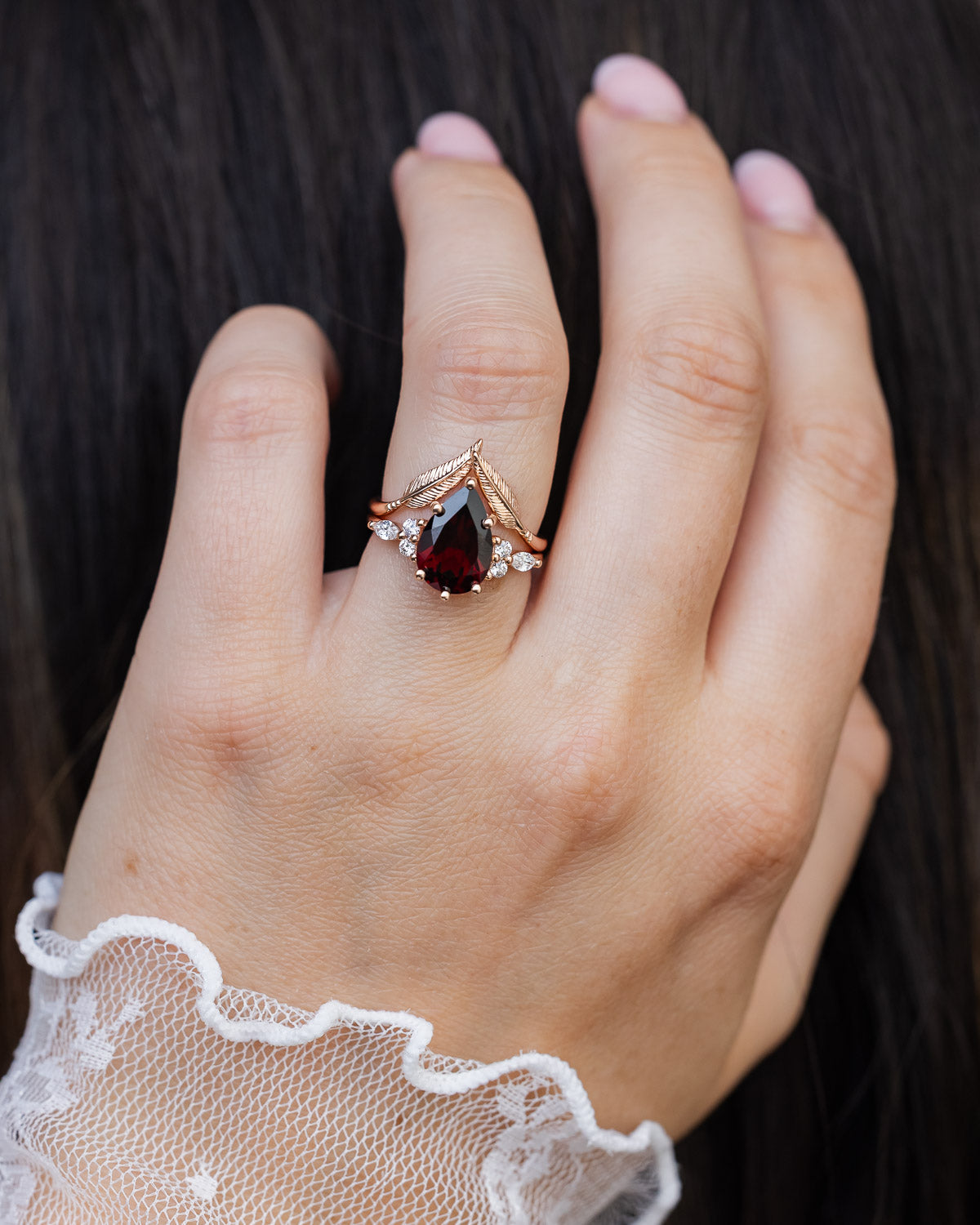 On hand photo of "Sage" - garnet women's engagement ring with diamond accents & "Fala" feather-style tracer
