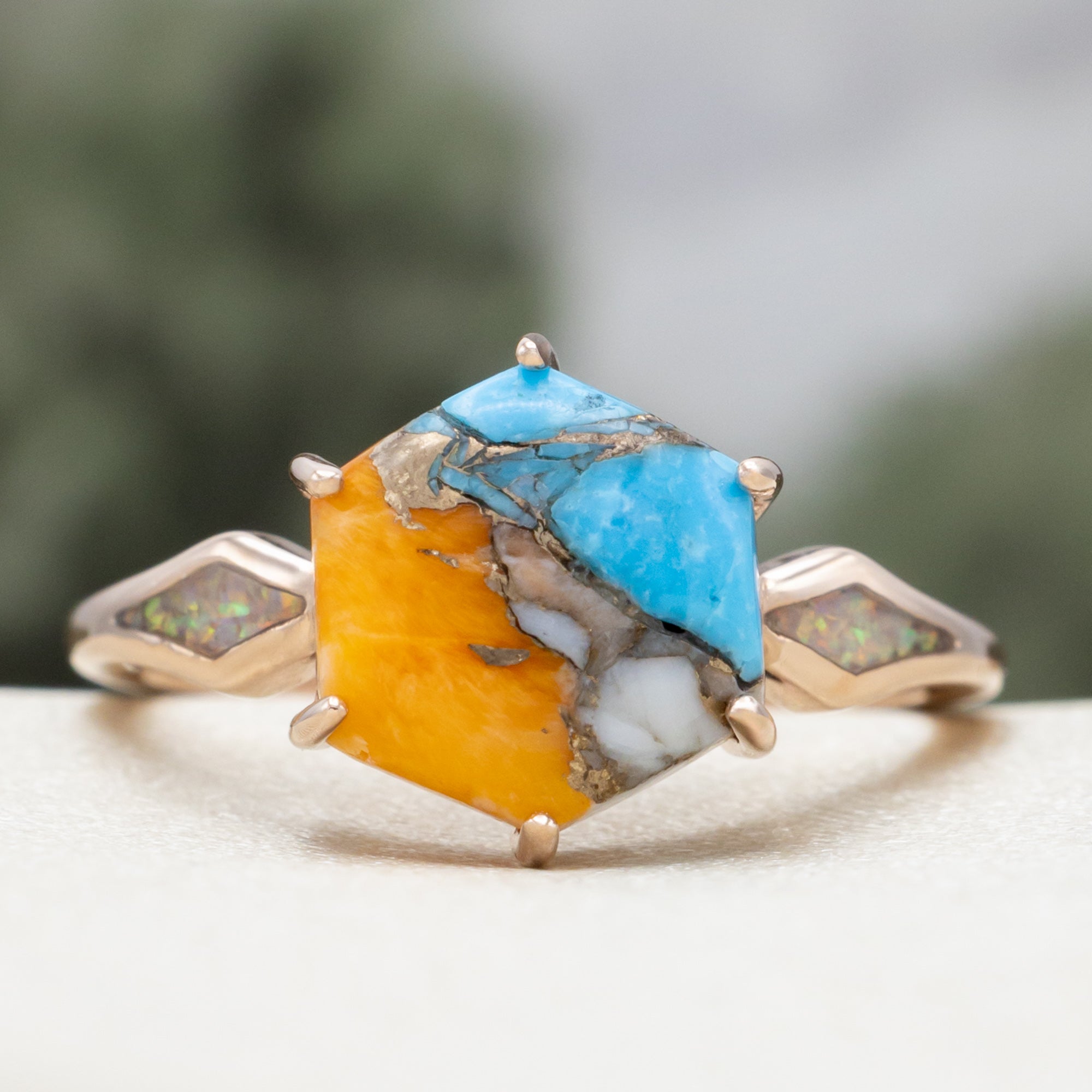 Rose gold ring with spiny turquoise center stone against a blurred background