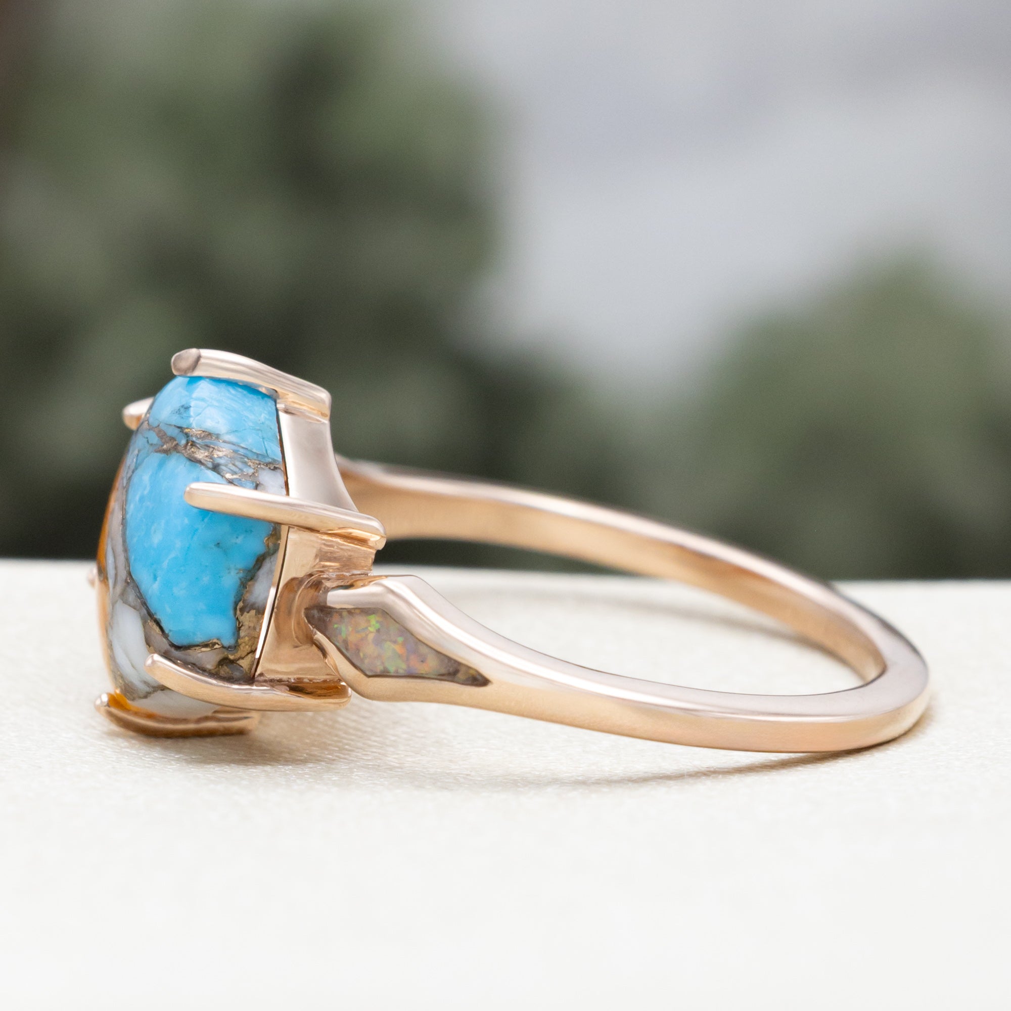 Rose gold ring with spiny turquoise center stone against a blurred background
