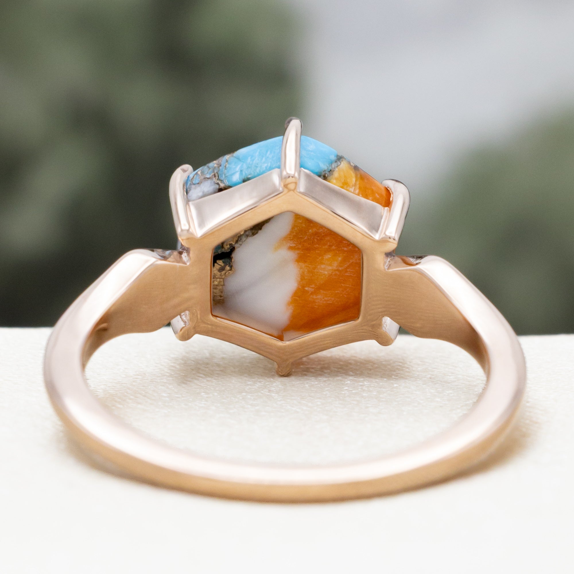 Rose gold ring with spiny turquoise center stone against a blurred background