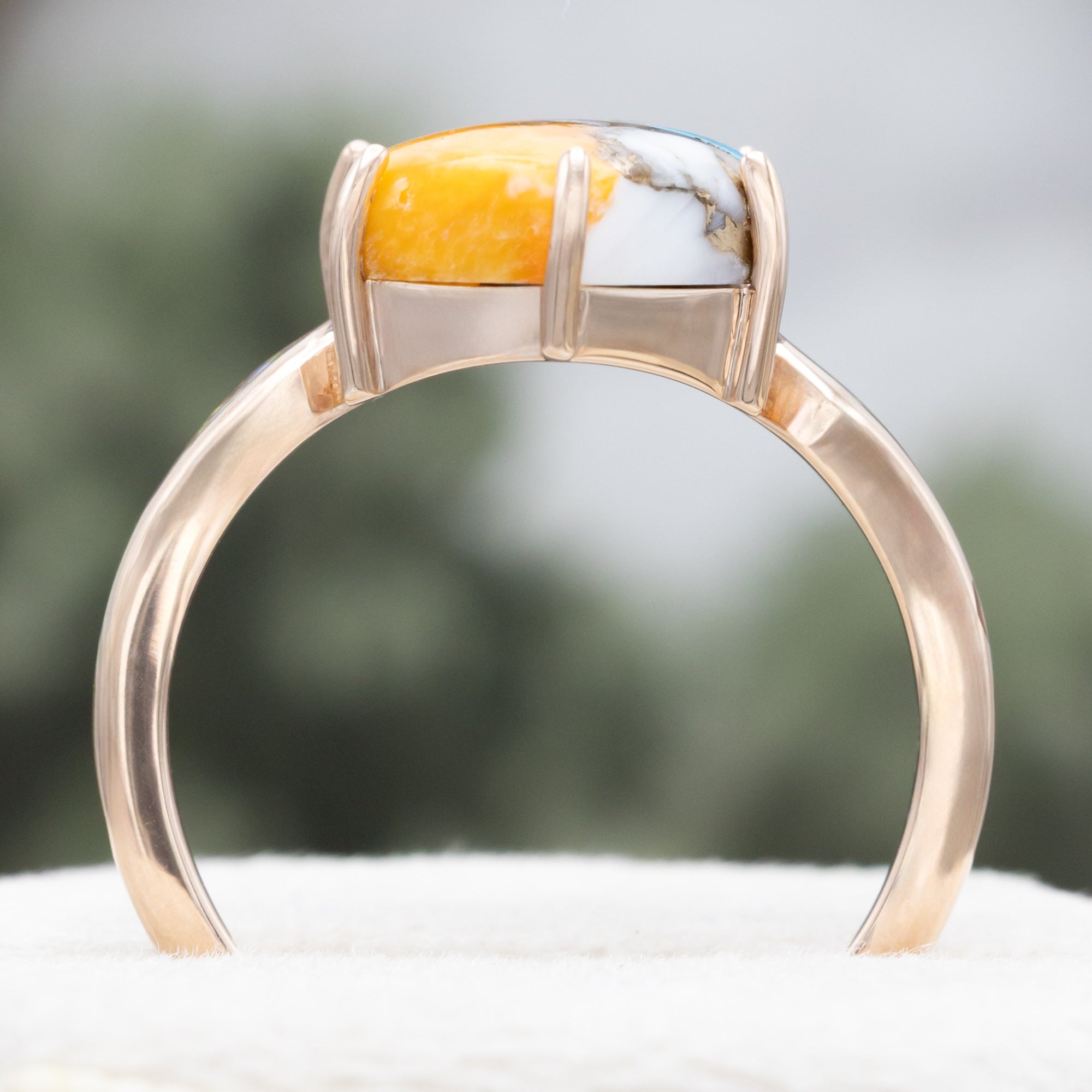 Rose gold ring with spiny turquoise center stone against a blurred background