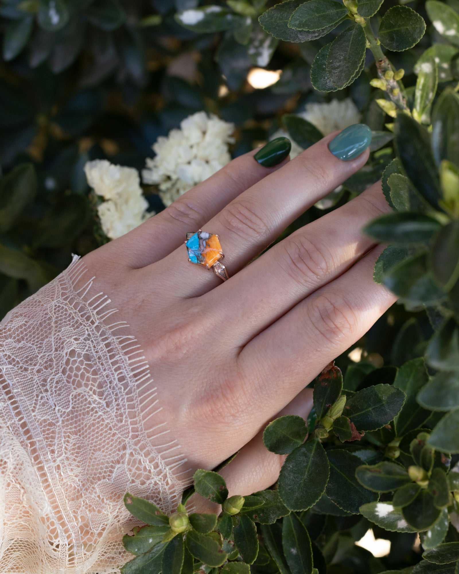 Ring with a spiny turquoise centerstone on a hand with a blurred floral background