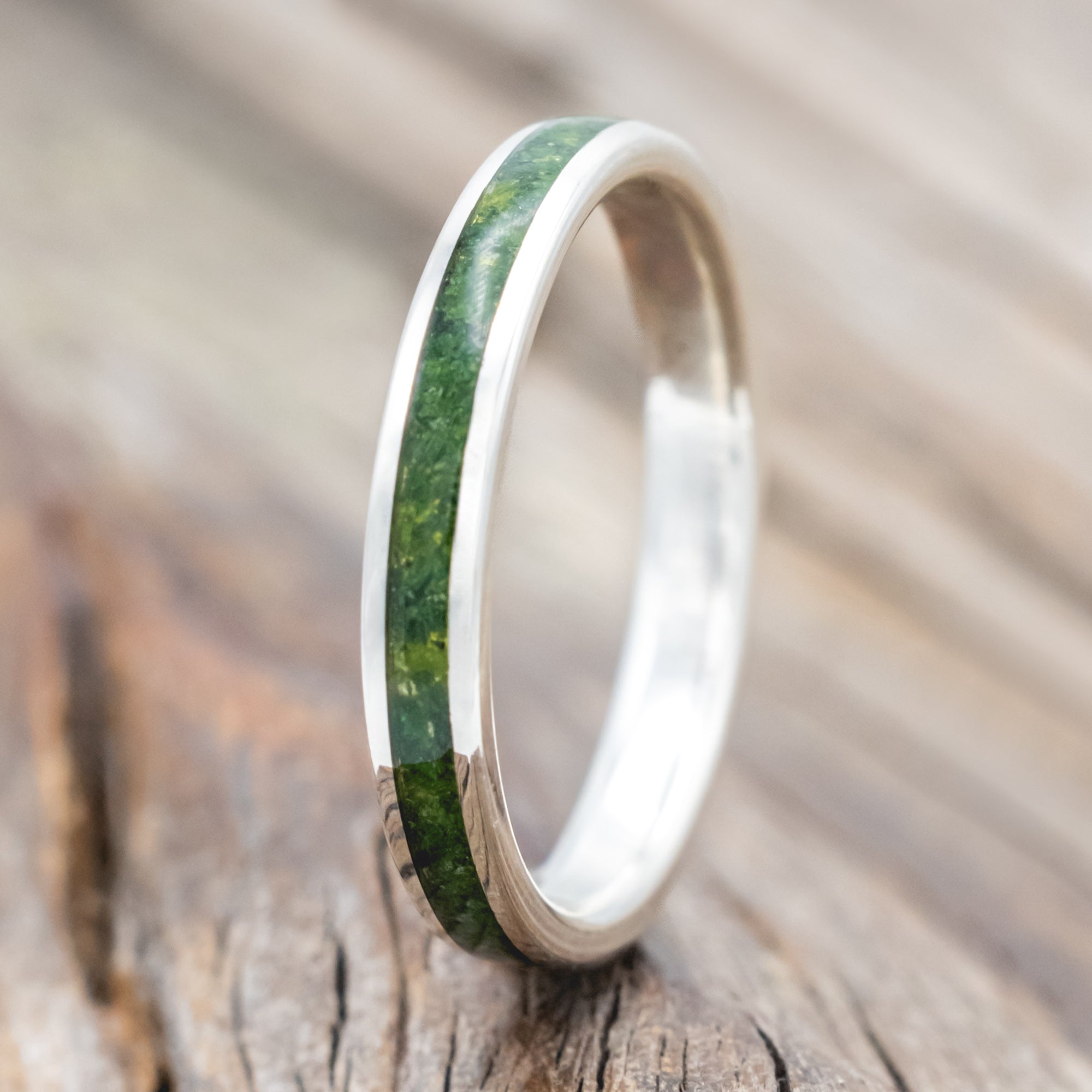 Silver ring with moss inlay on a wooden surface