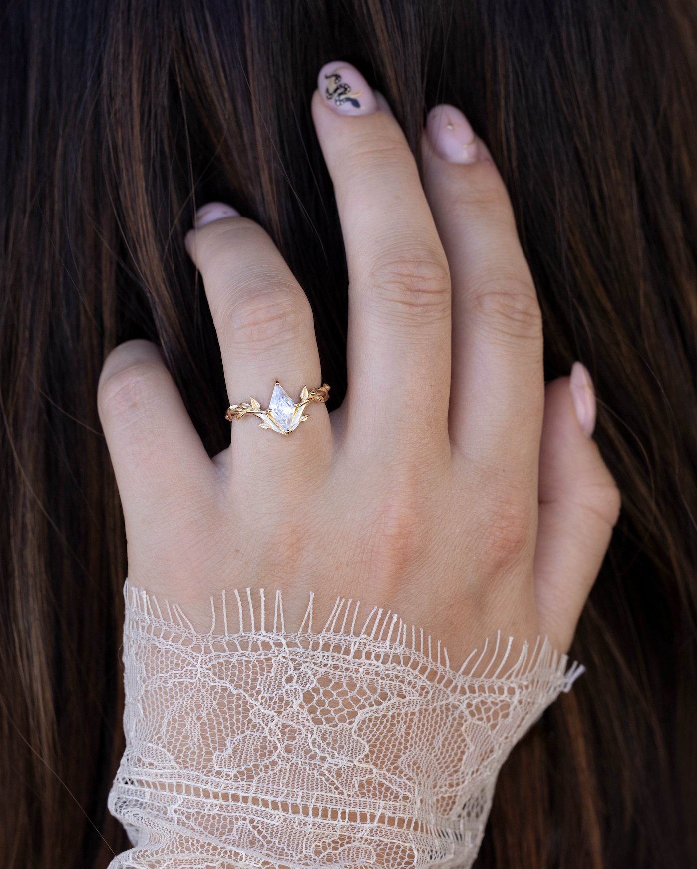 Hand wearing a gold ring with a Moissanite center stone, set against a dark background