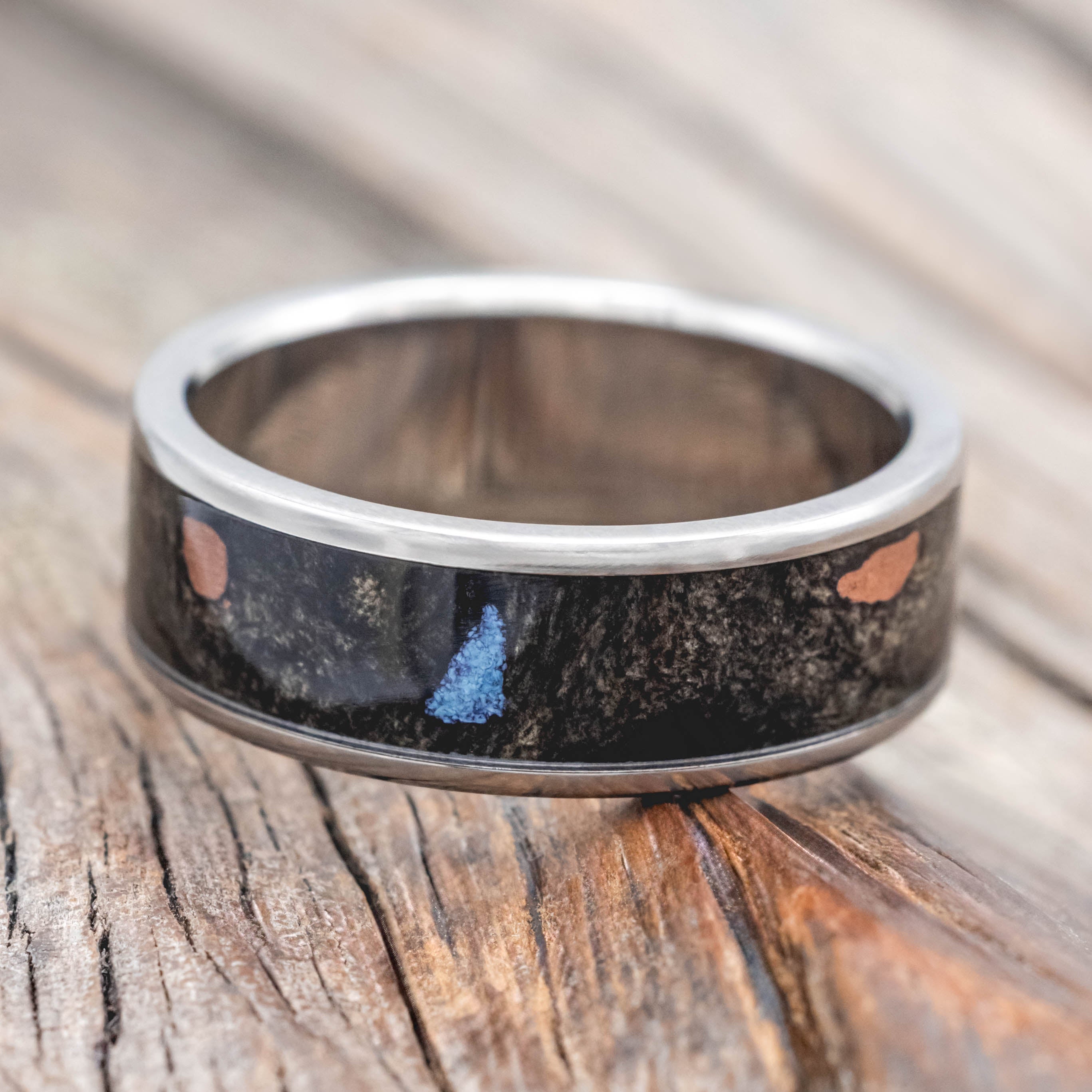 Wedding ring with buckeye burl with turquoise and powdered copper mix on a wooden surface