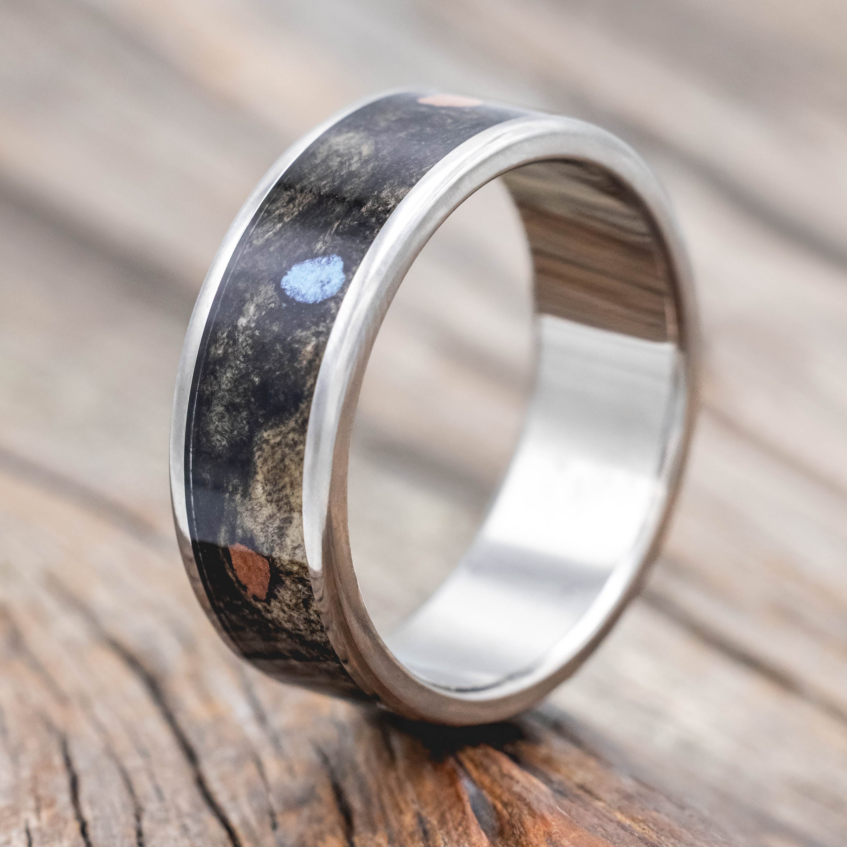 Wedding ring with buckeye burl with turquoise and powdered copper mix on a wooden surface