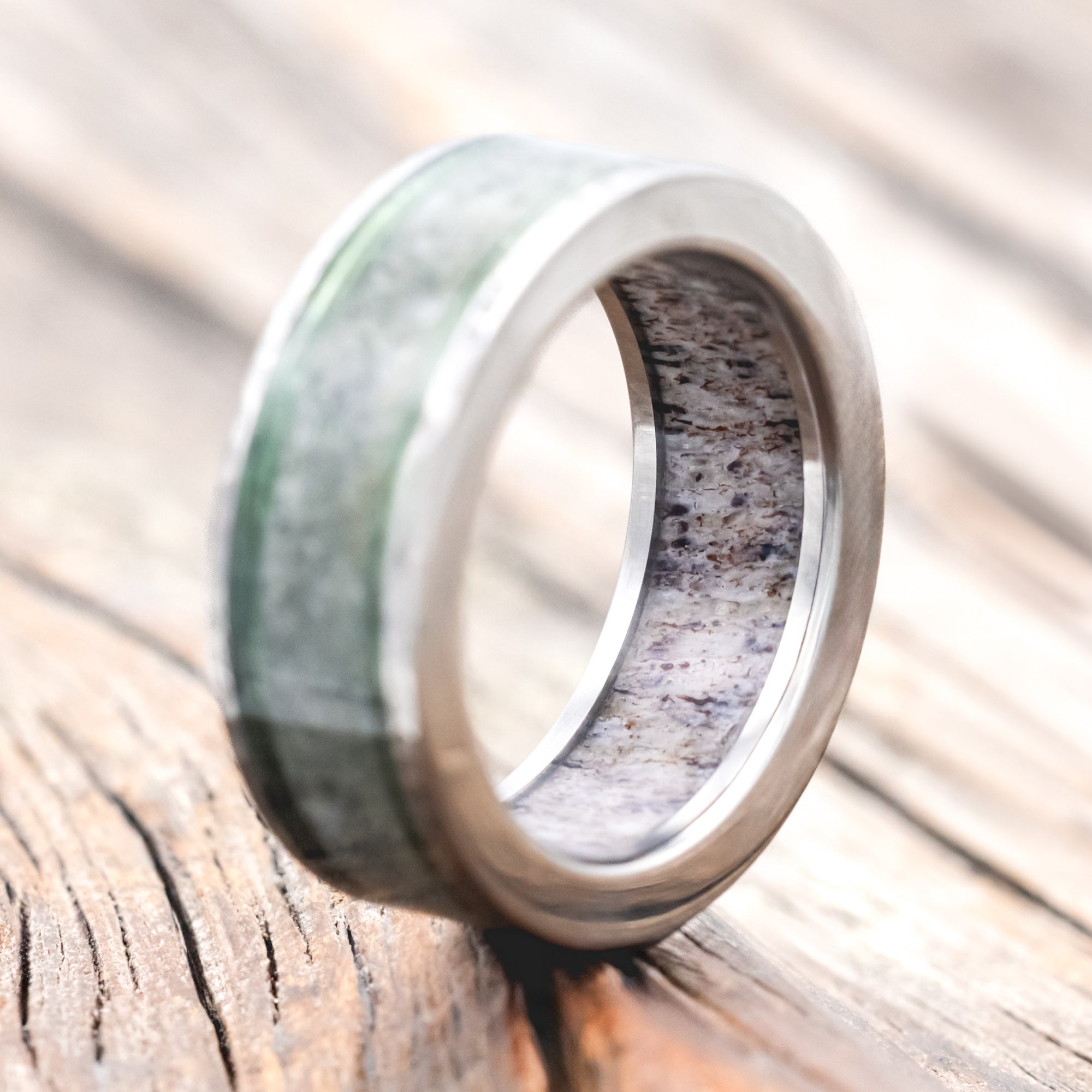 Ring with green and silver design on a wooden surface