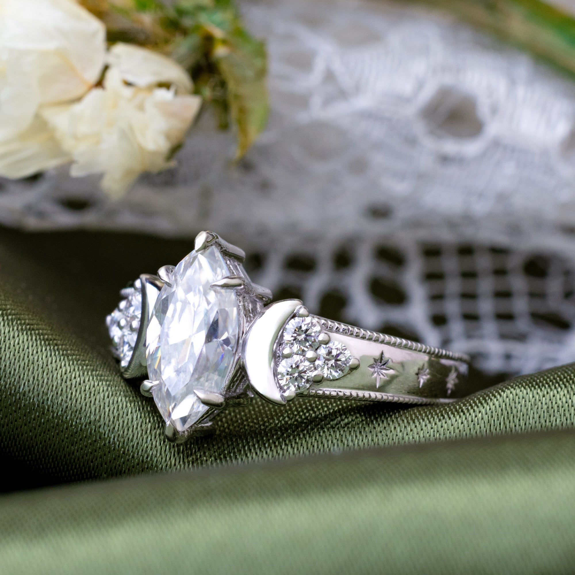 White gold ring with a large moissanite on a green fabric background