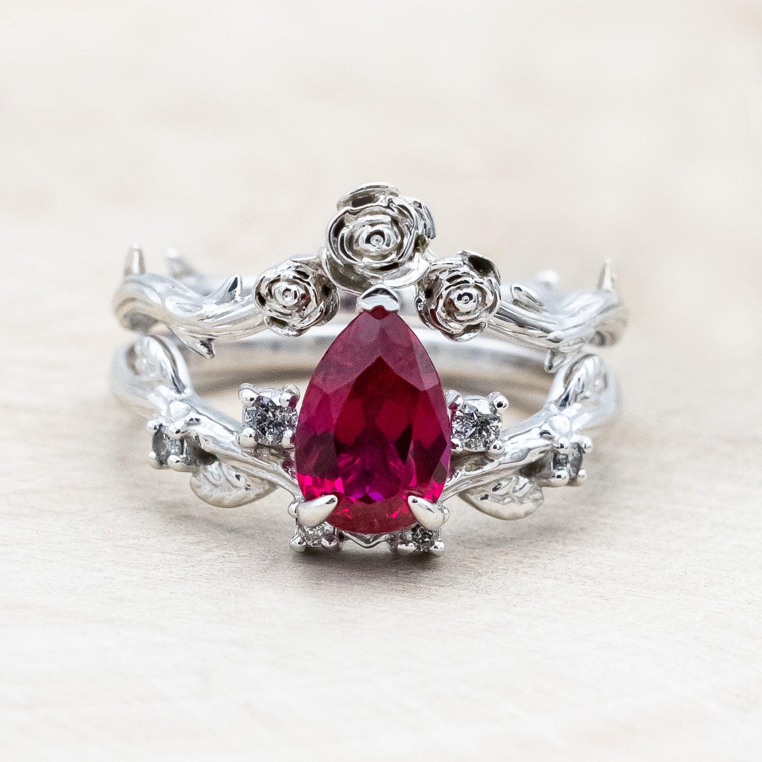 "Harlow" pear cut ruby engagement ring with salt & pepper diamond accents on a branch-inspired band and floral style tracer