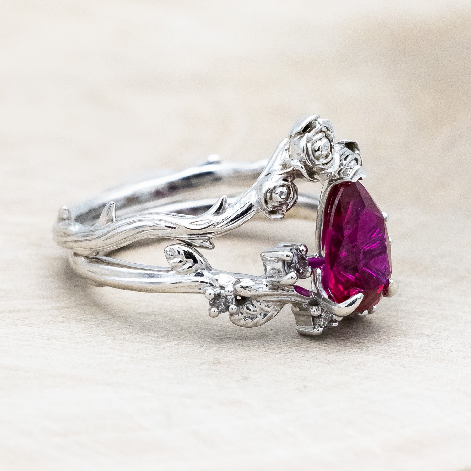 "Harlow" pear cut ruby engagement ring with salt & pepper diamond accents on a branch-inspired band and floral style tracer