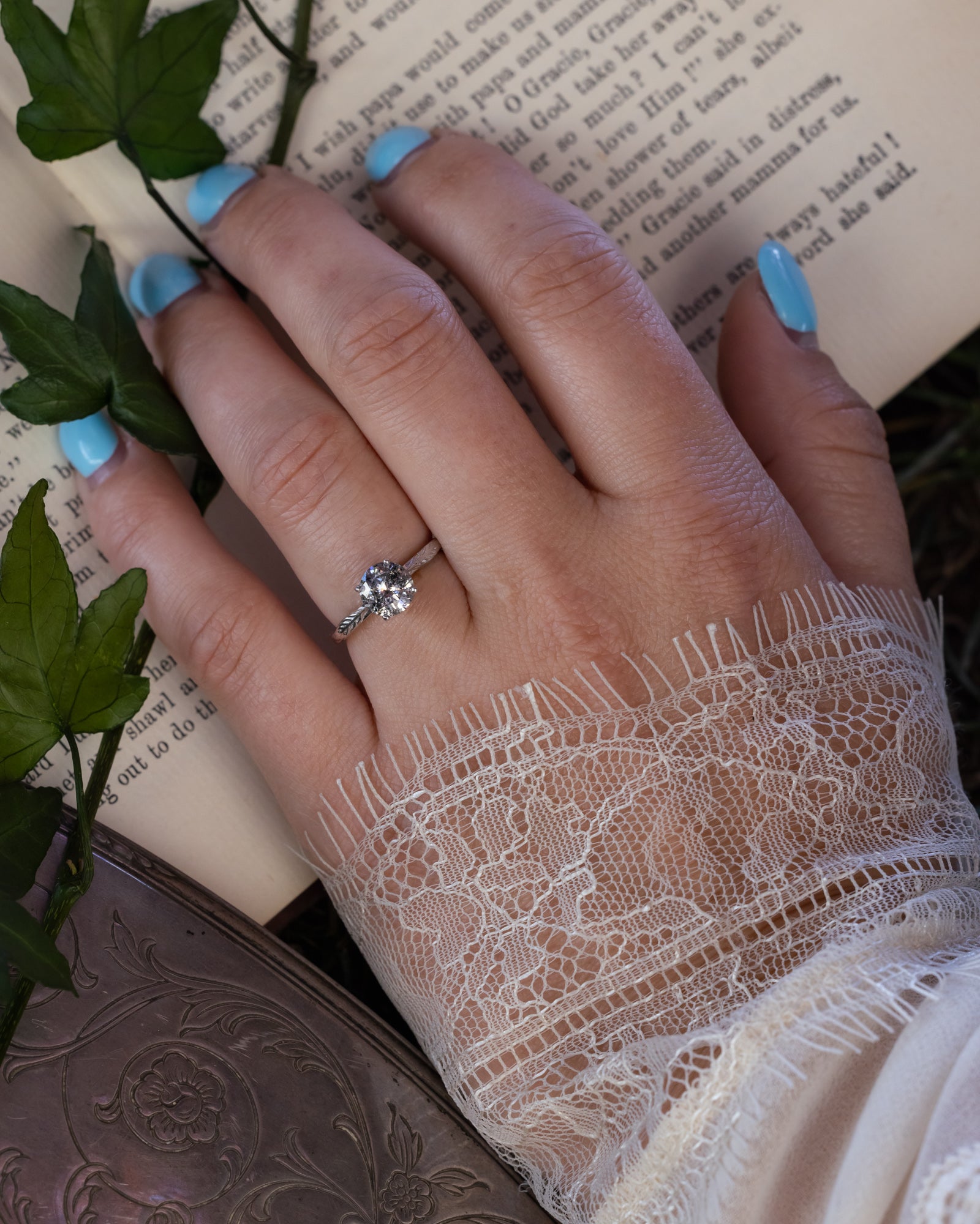 White gold ring with salt & pepper diamond against a book page.