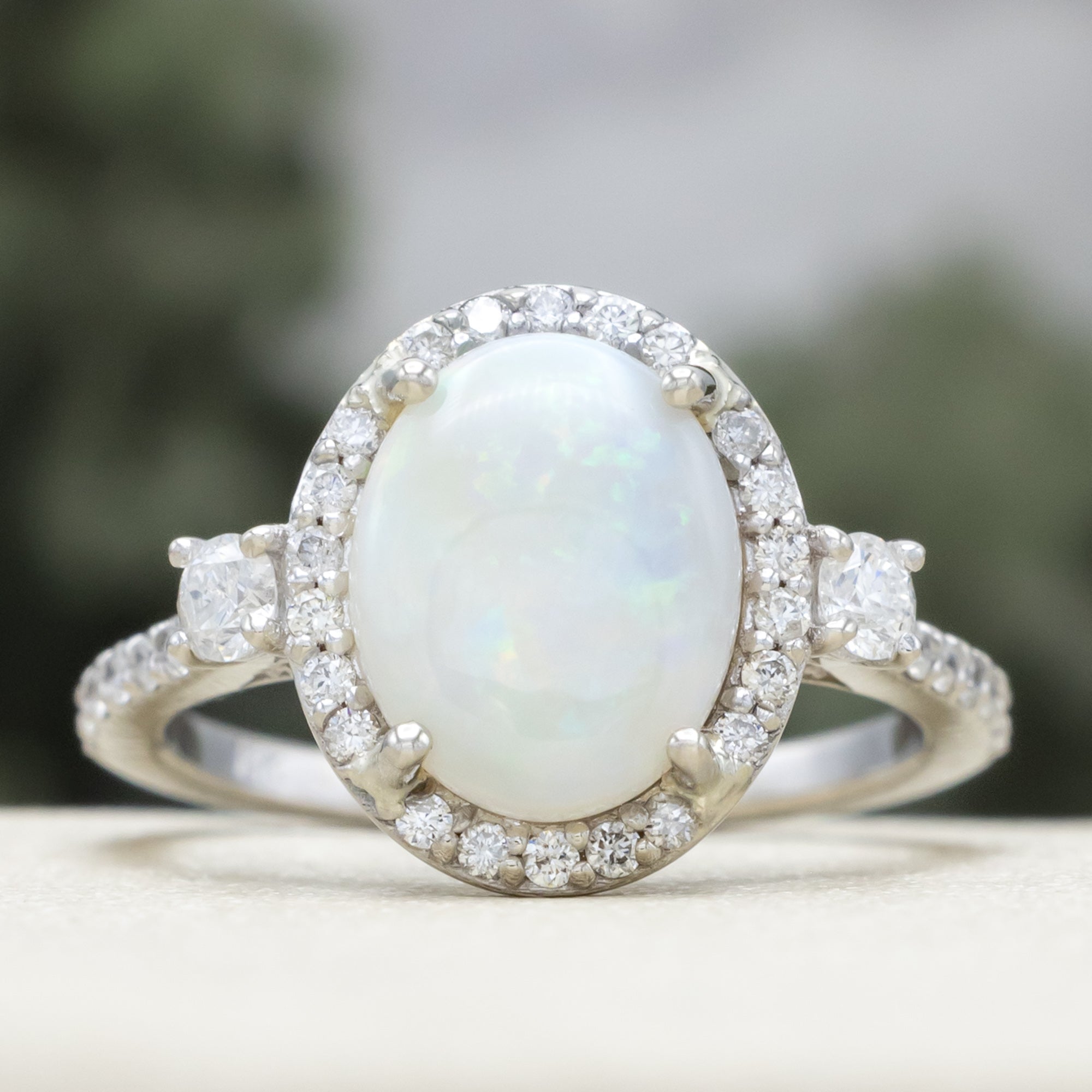 White gold ring with an oval opal stone and diamond accents on a neutral background