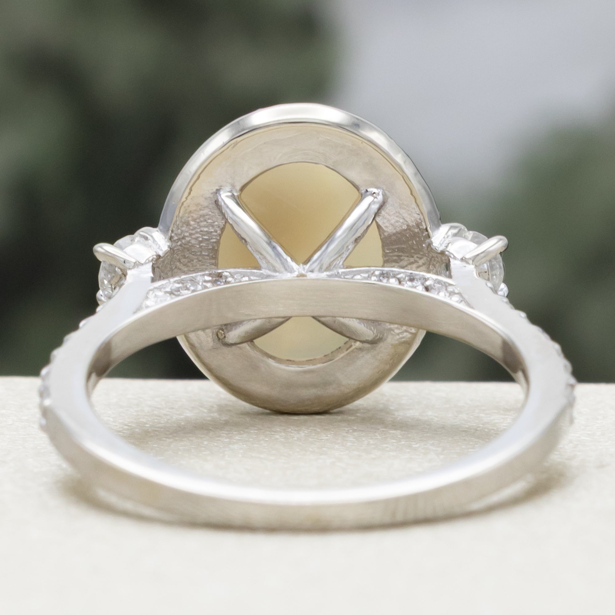 White gold ring with an oval opal stone and diamond accents on a neutral background