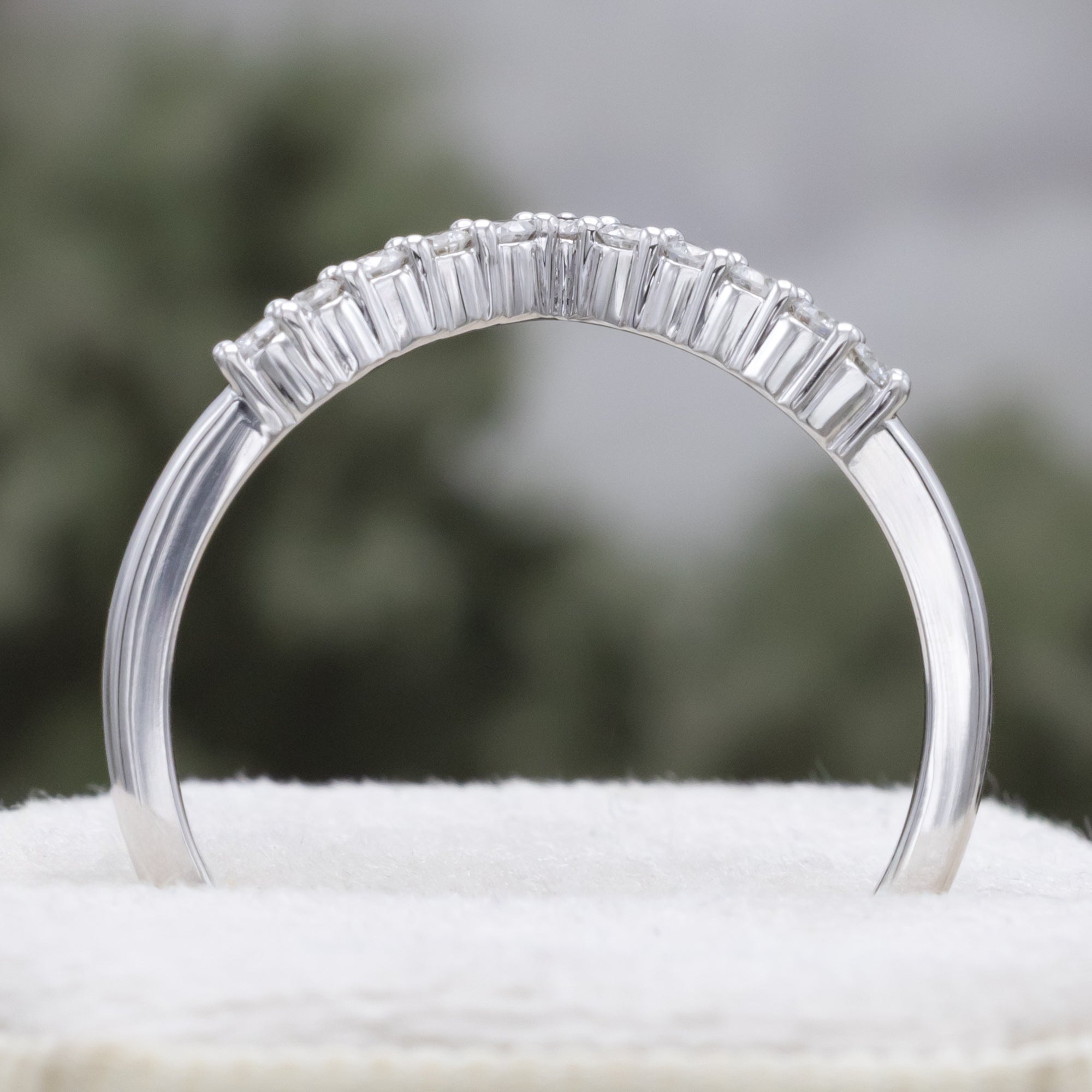 White gold ring with diamond accents on a blurred natural background
