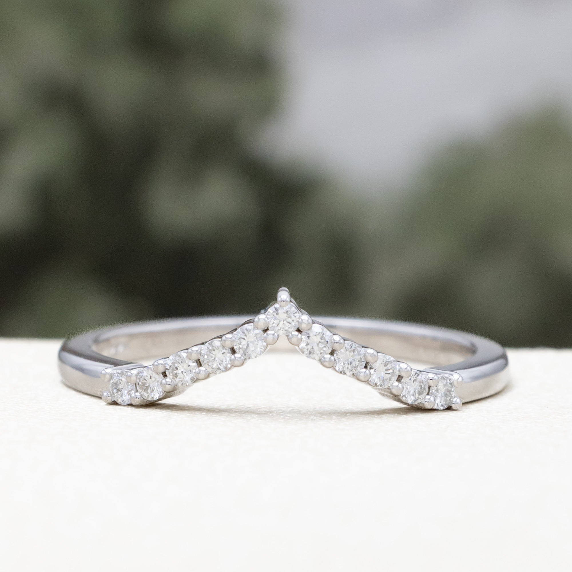White gold ring with diamond accents on a blurred natural background
