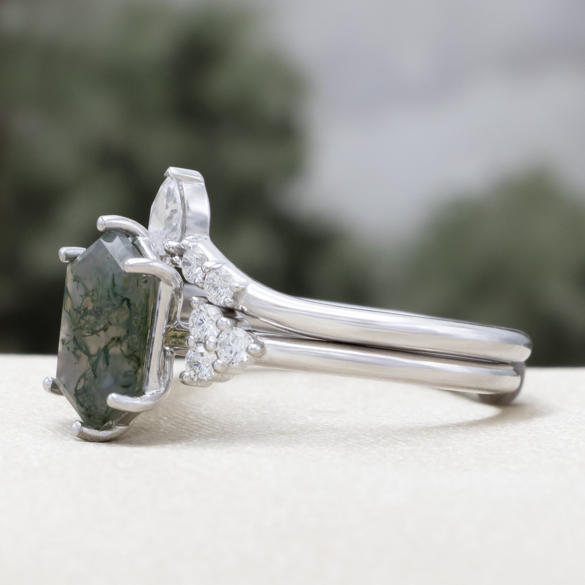 14K white gold engagement ring and tracer with moss agate and diamond accents on a blurred background