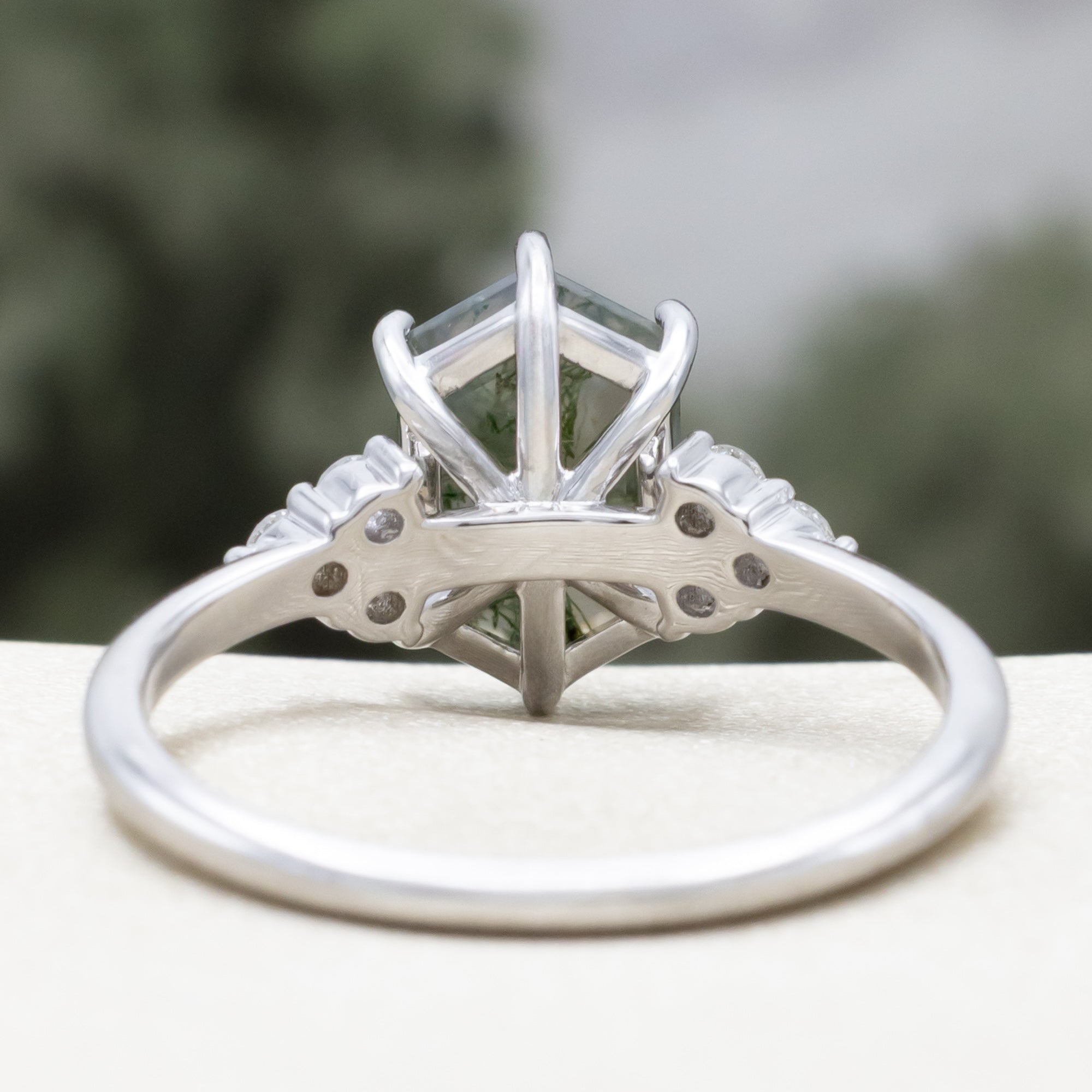 14K white gold engagement ring with moss agate on a blurred background