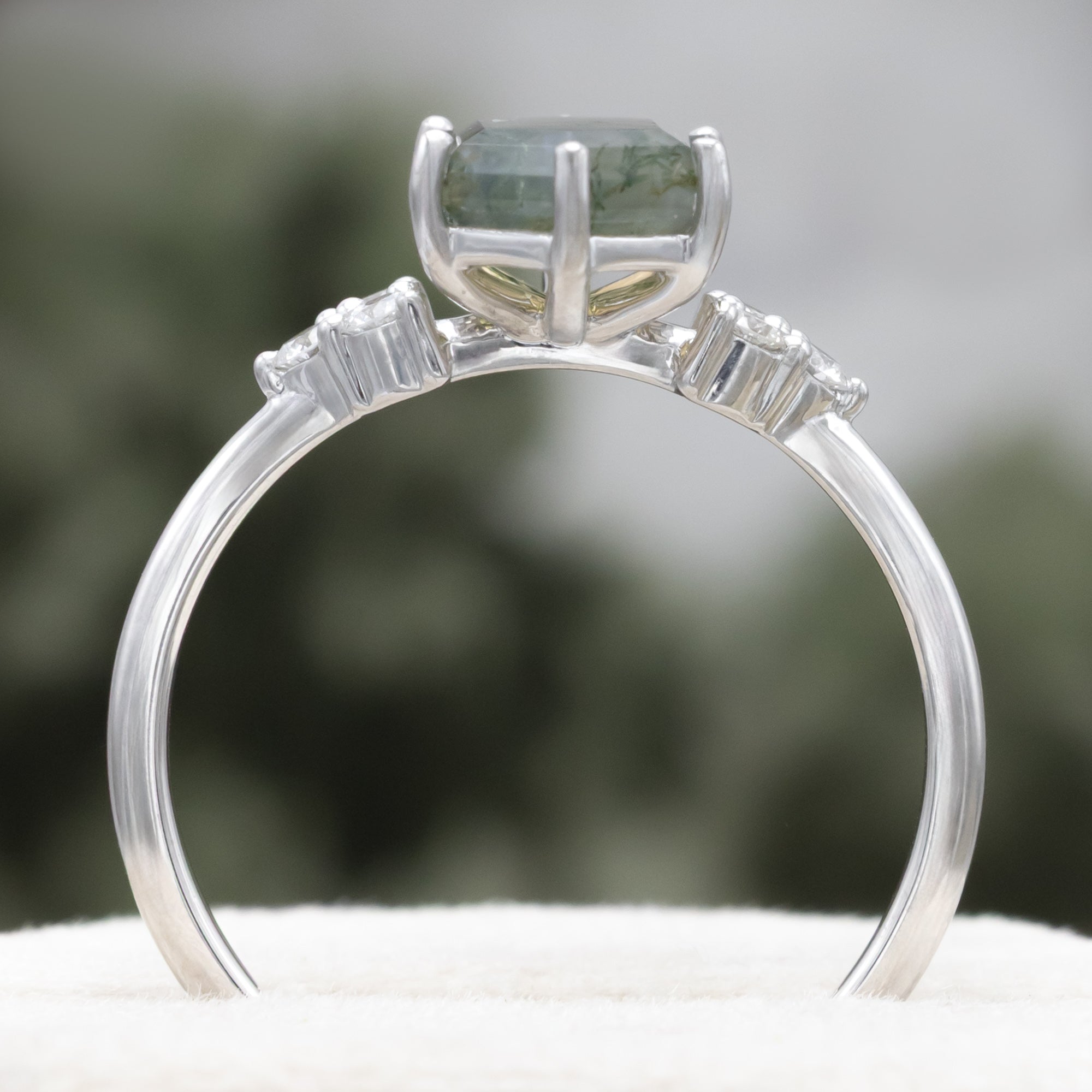 14K white gold engagement ring with moss agate on a blurred background