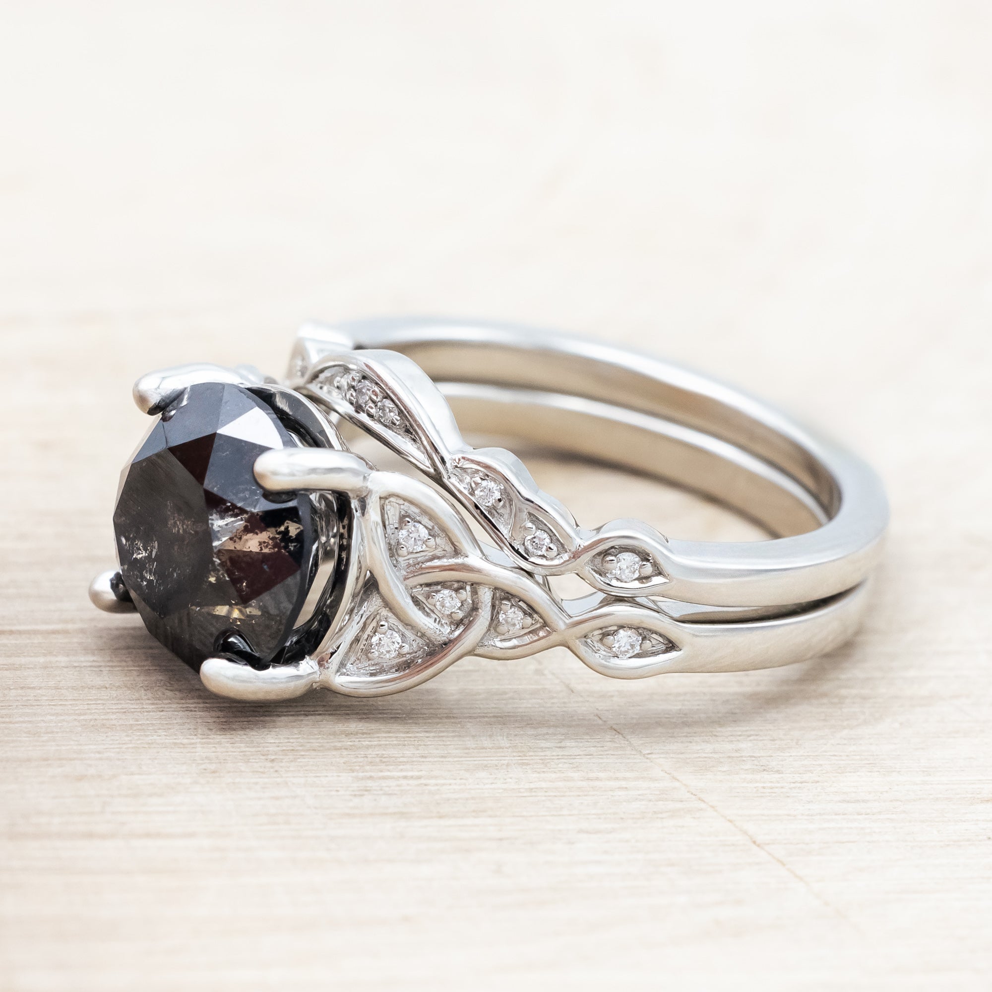14K white gold ring with a salt & pepper diamond on a wooden surface