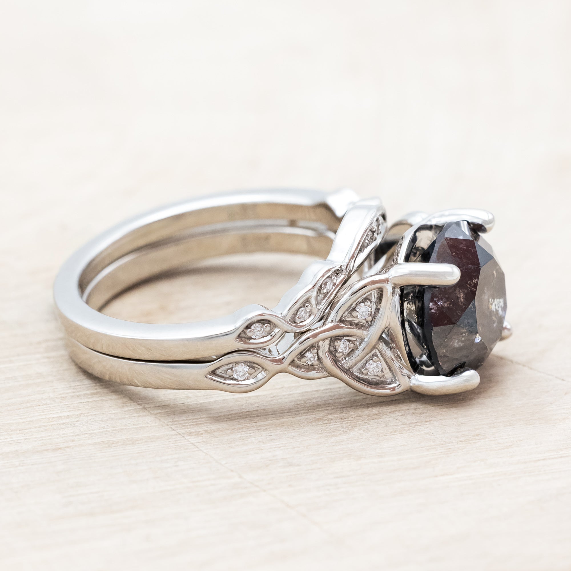 14K white gold ring with a salt & pepper diamond on a wooden surface