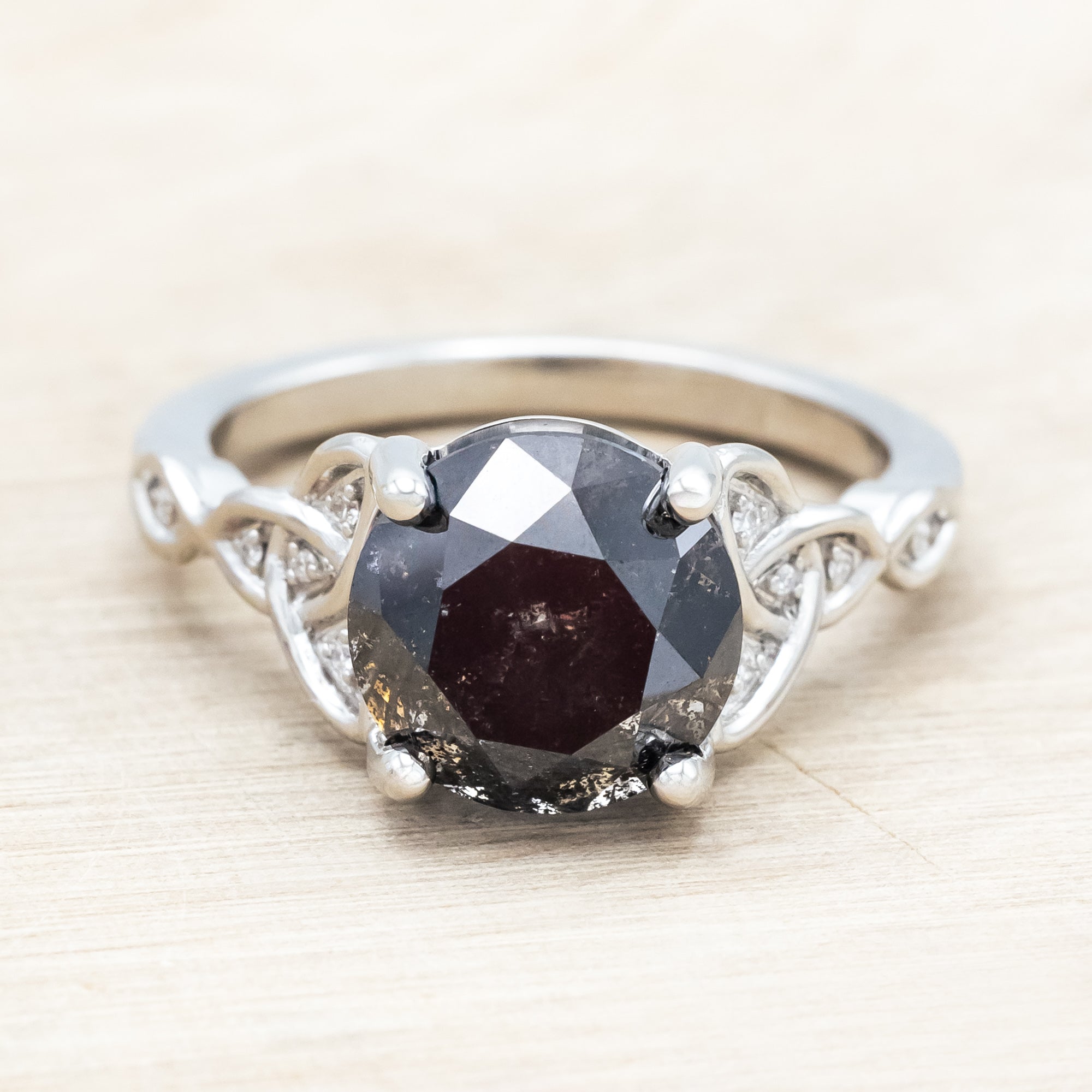 14K white gold ring with a salt & pepper diamond on a wooden surface