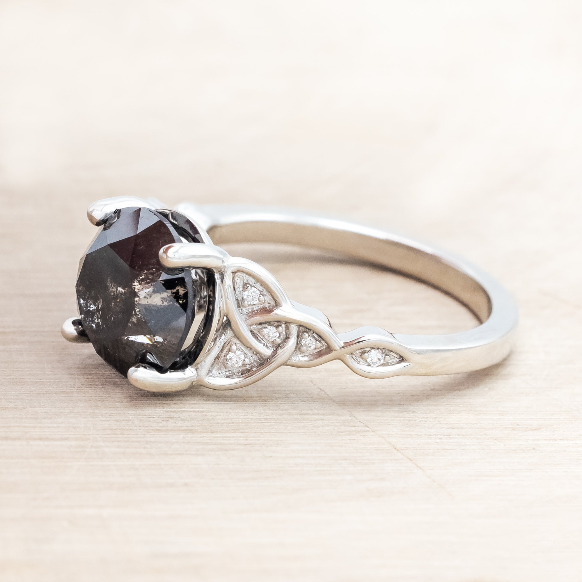 14K white gold ring with a salt & pepper diamond on a wooden surface