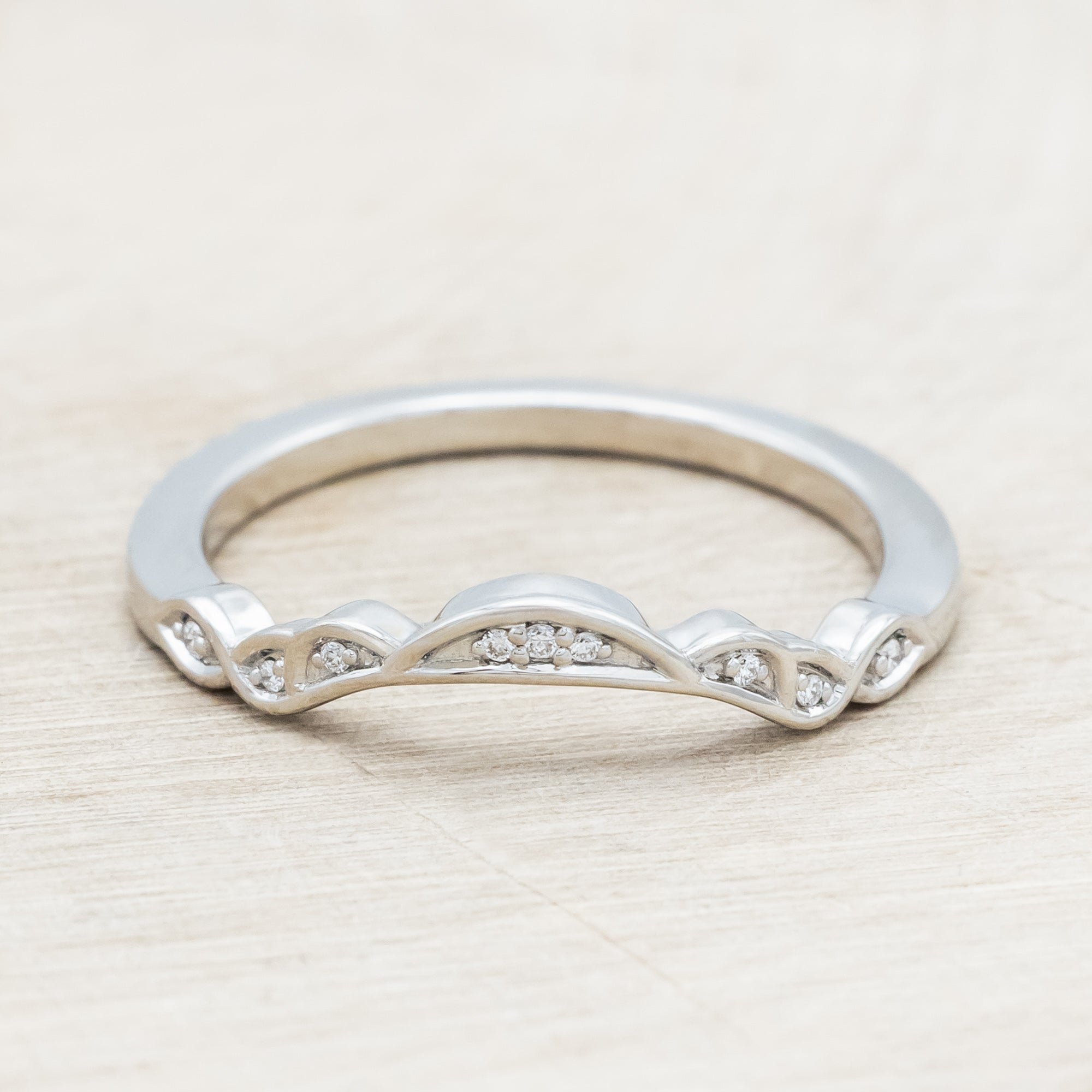 14K white gold ring with diamond accents on a wooden surface